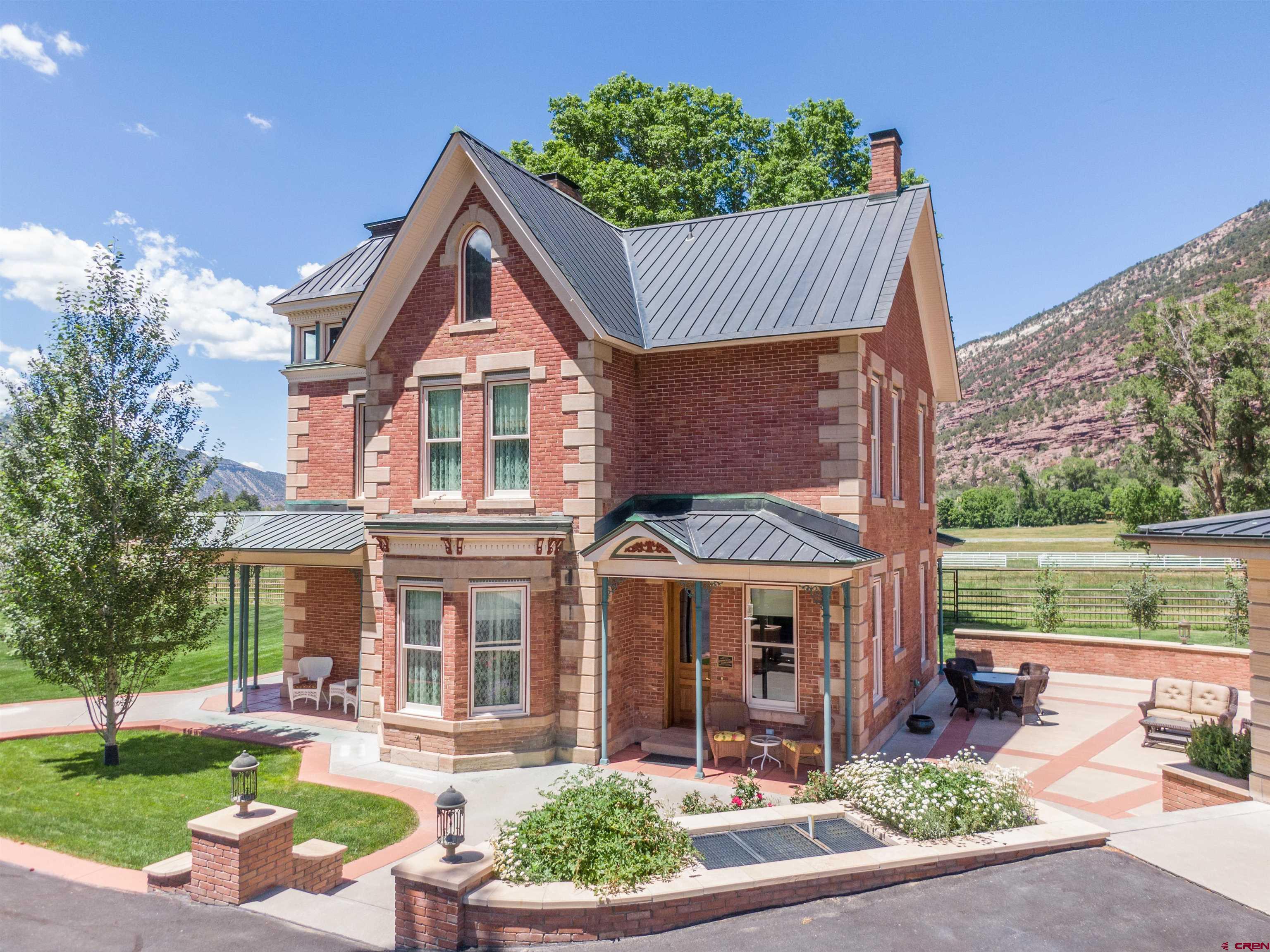 This Gorgeous Victorian Home is located in the beautiful valley just north of Ouray.  Surrounded by the majestic San Juan Mountains, this historic gem is listed on the National Historic Registry. Construction began in 1886 and was completed in 1888 by George Andrew Jackson, who is credited with discovering the first commercial gold deposits in Colorado and was the nephew of Kit Carson. The property underwent many changes over the years, eventually falling into disrepair and sitting vacant for some time. In 2000, a local judge and builder purchased the home and began an incredible 10-year restoration project. Updates included all-new plumbing and electrical systems, foam-insulated interior walls, a copper roof, new subfloors, central heating and cooling, and new doors and windows.  The next owners, who purchased the home in 2011, completed the restoration by 2013. The level of care and craftsmanship throughout is truly something you must see to appreciate. Custom walnut millwork, crafted by a local artisan, adds elegance to the interior doors, windows, baseboards, and cabinetry. Much of the original gingerbread detailing still graces the exterior, along with original elements of the staircase that leads from the foyer to the second level. Marble and wood floors are featured throughout the home.  The kitchen features reproduction Heartland appliances—including two ovens, a broiler, warming drawer, refrigerator, and dishwasher—creating a charming vintage ambiance with modern functionality. The finished third-story attic offers an office space and two bonus rooms.  There are three beautifully restored bedrooms, including an elegant primary suite, and three full bathrooms. The lawn irrigation system is fed by a 100-gallons-per-minute water well. Priority water rights on the Hosner Brownyard Ditch feed the pond and over an acre of agricultural land. The house itself is supplied by Tri-County Water.  The three-car garage includes in-floor heating, a fourth full bathroom, and a parking pad with a 30-amp plug for your RV. The private, expansive patio features an outdoor kitchen—perfect for entertaining.  The home is ideally located near a gravel road, perfect for biking to Ouray or Ridgway, and it's only 30 minutes from world-class backcountry skiing on Red Mountain Pass.  Call today for a showing!