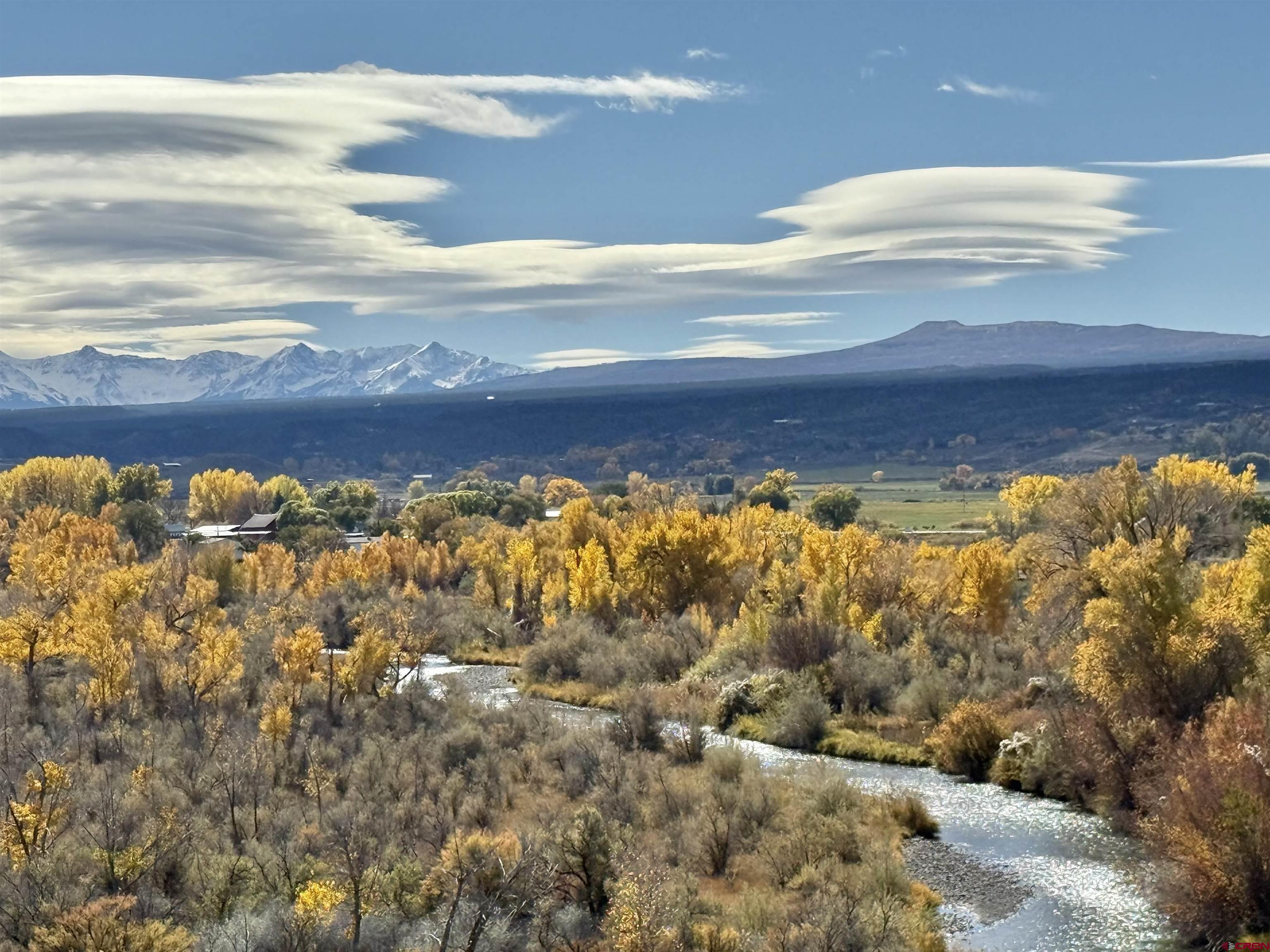 An unexpected opportunity arises as this sought-after home returns to the market. Refined Colorado Living — Now Priced to Inspire. Perched above the Uncompahgre River with commanding, unobstructed views of the San Juan Mountains, this exceptional Colorado estate offers a rare combination of privacy, elegance, and natural beauty. Situated on a 1.11-acre irrigated escarpment, the property’s elevated setting permanently protects its panoramic vistas, creating a truly irreplaceable backdrop. Mature, meticulously maintained landscaping with a drip irrigation system enhances the home’s serene, park-like ambiance.  The interior has been thoughtfully redesigned with a sophisticated open floor plan that is both inviting and impressive. Upon entry, the home reveals a gracious formal dining room, an expansive living area anchored by a fireplace, and a beautifully appointed kitchen featuring granite countertops, premium stainless steel appliances (all included), abundant custom cabinetry, and a sun-filled breakfast nook framed by breathtaking mountain views. Glass doors lead to a generous covered deck—perfect for refined entertaining or quiet mornings overlooking the valley below.  The primary suite is a private retreat, offering a spa-inspired bathroom, walk-in closet, and adjacent flexible space ideal for a library, executive office, or fourth bedroom, with a nearby full bath. The main level also includes two spacious guest bedrooms, a full guest bath, and a well-designed laundry room with sink, extensive storage, and included washer and dryer—delivering the ease of true single-level living.  The finished lower level extends the home’s luxury and versatility, featuring an expansive living area, additional kitchenette ideal for multigenerational living or extended guests, and a large storage room. Step outside to the covered patio and continue to enjoy the home’s extraordinary setting and views.  Completing the property is a detached 3+ car garage with epoxy floors and workshop space, offering both function and refinement. Ideally located near world-class skiing, hiking, biking, and fly-fishing, this remarkable residence represents the pinnacle of Colorado living—an opportunity rarely offered and not to be missed.