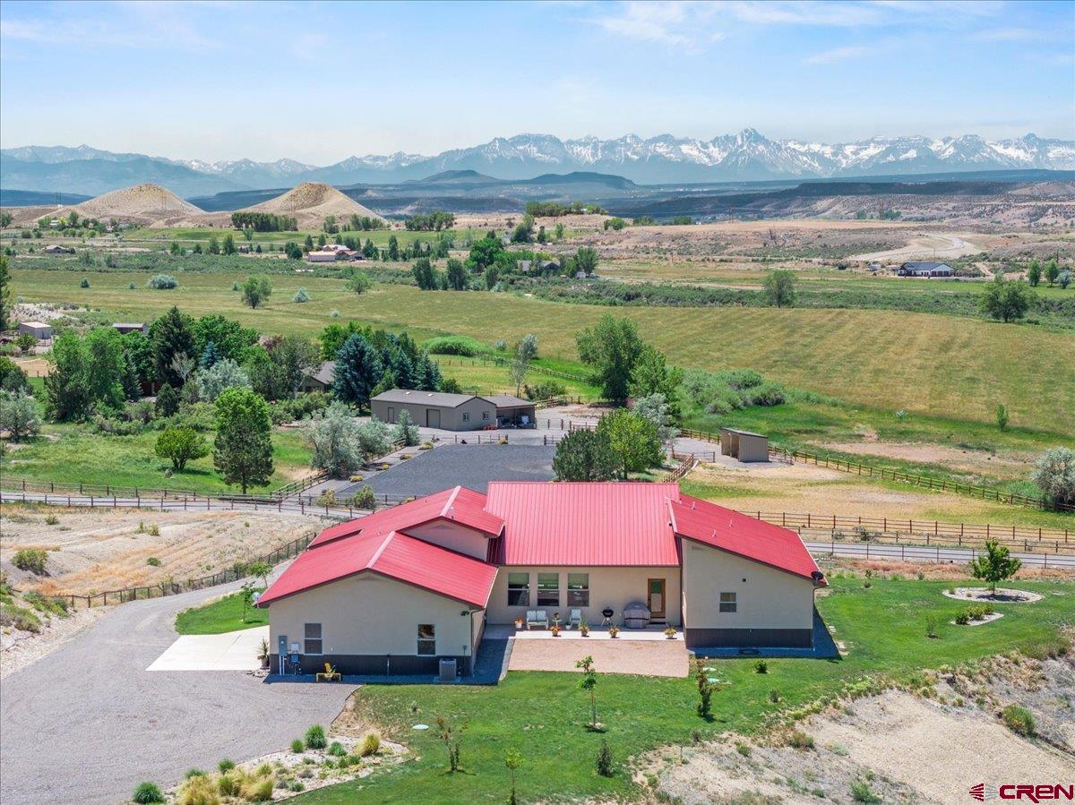 Built in 2018, this modern Mountain View home offers refined sophistication and thoughtful design across 3 bedrooms, 3 baths, a versatile flex room, and an oversized 3-car garage. Set on 4.84 irrigated acres with sweeping views of the San Juans, Grand Mesa, and Cimarron Ridge, the home showcases scratch-resistant laminate and tile flooring, quartz countertops, high-end KitchenAid appliances, and Delta fixtures. The great room features expansive Jeld Wen windows with automatic Hunter Douglas blinds in the great room and a propane gas-log fireplace. Enjoy comfort and utility with a large 4’ crawlspace, forced air system, and hot tub wiring in a private courtyard. The exterior includes a metal roof with gutters, a 500-gallon leased propane tank, a 26-zone Rainbird irrigation system (5HP pump with 3 shares of Uncompahgre Valley Water Users Association), and a beautifully built front pipe fence in 2023. Bonus features include a 24x24 shop with a tall overhead door, bright LED lighting, and a farmer’s faucet in the south field. The garage is wired for a welder, and conduit is in place for Elevate fiber internet. This is mountain living with style, space, and high-end infrastructure—ready for your lifestyle.