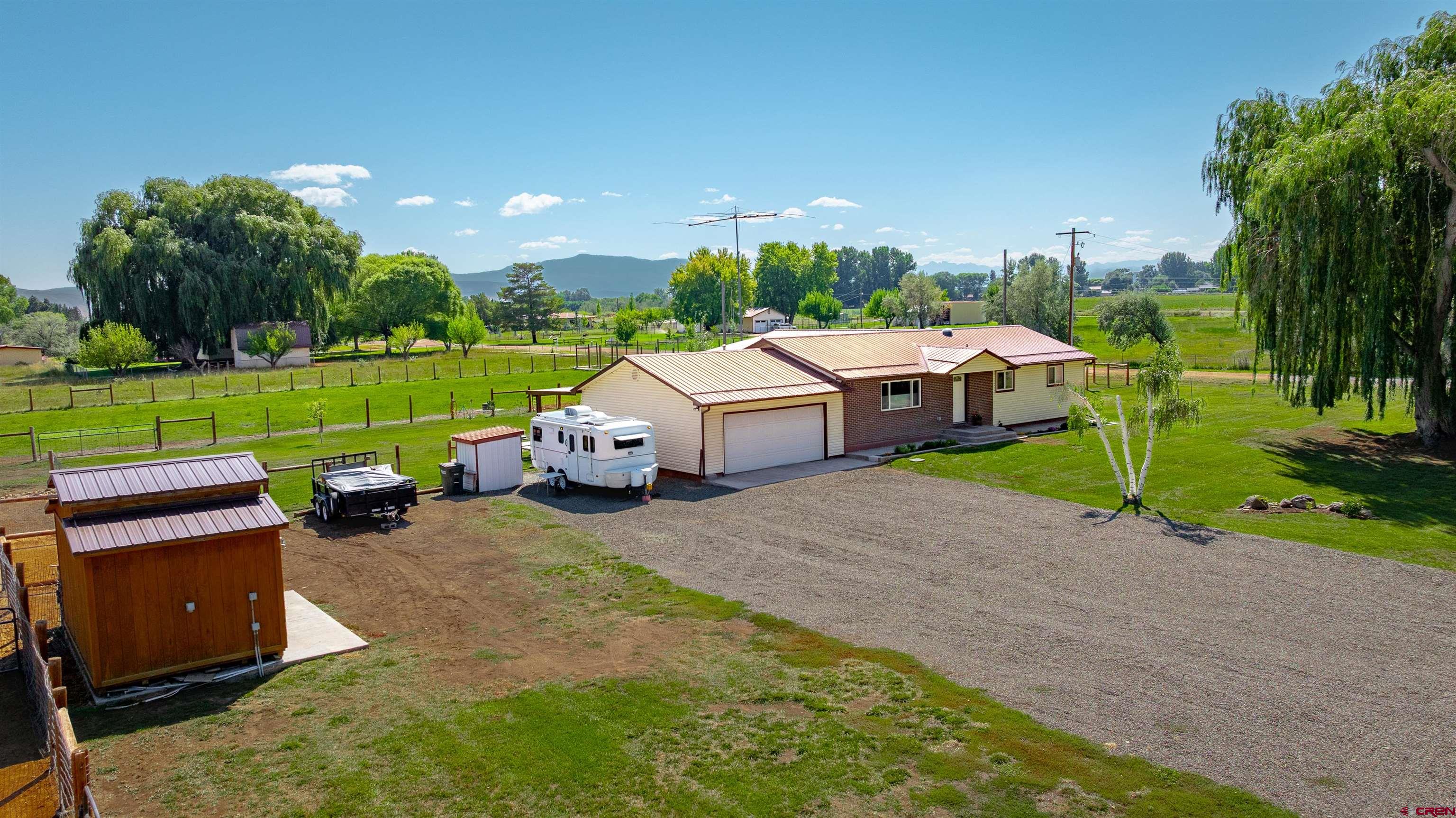 Welcome to relaxed country living on Spring Creek Mesa, where wide-open skies and thoughtful updates create a true retreat. This renovated 4-bedroom, 3-bath farmhouse offers 2,192 sq ft of inviting living space on 3 irrigated acres, creating room to breathe both indoors and out.  Morning light fills the living room through a large picture window, while the open kitchen becomes the heart of the home with knotty alder cabinetry, granite countertops, river rock backsplash, black stainless appliances, and sweeping eastern views. Two private en suites feature custom tile showers, granite vanities, and rain-glass doors, creating comfortable spaces to unwind. A flexible bonus room off the dining area adapts easily as a sunroom, family room, home office, or creative space. Solar tubes enhance the home with soft daylight throughout.  Outdoors, enjoy a fully functioning mini-farm with fenced pastures, a horse shelter, hay barn, tack shed, chicken coop with automatic door, multiple frost-free spigots, and a fenced orchard. Mature landscaping frames a large covered patio and Trex deck with sunshade, ideal for morning coffee, evening gatherings, or simply enjoying the quiet surroundings. No HOA. Schedule your private showing today!