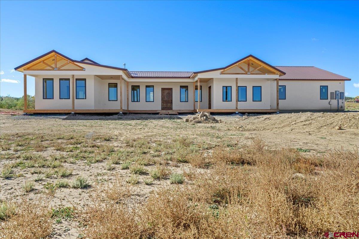 This 2800+ sq ft newly built custom home sits on a stunning 3 +irrigated  acre lot overlooking beautiful Spring Creek Mesa. The residence features four bedrooms and three bathrooms, with an oversized 3 car-attached garage. Spacious kitchen with Quartzite countertops, ample counter space, and two ovens for convenient cooking.  The large 7’ x 15’ walk-in pantry is spacious with plenty of room for storage of small appliances and extras. There is a separate dining area that has built in custom cabinets and Alder doors leading to the large deck for entertaining guests. The large & spacious living room include natural hickory flooring and 10 ft ceilings throughout the entire home. There is built in shelving and a beautiful stone surrounding wood burning stove. The large windows in the living room add natural light and highlight the views of beautiful Spring Creek Mesa. The primary bedroom is large and continues with the natural hickory flooring. The bathroom features a stand-alone tub, large walk-in tiled shower, and his & hers Quartzite counters with double sinks. There is also a large walk-in closet. The three additional bedrooms also have hickory flooring and Alder doors. There is a half bath with a sink conveniently located off the garage entrance and large mud room. Outside features include natural wood decking in front and the back of the home. There are large natural wood exposed beams on the front and back porches with tongue and grove soffits. The owner originally built this home for himself, so you know there was a little extra care put in the construction, this is not your typical spec home. This house is well-built from foundation to roof and includes a protective French drain for the foundation.   The insulation is also the best you can get with closed cell spray foam in the walls and roof decks. The paint is eco-nontoxic. The base is secured atop a 16-inch thick sandstone layer, providing reliable support and stability.