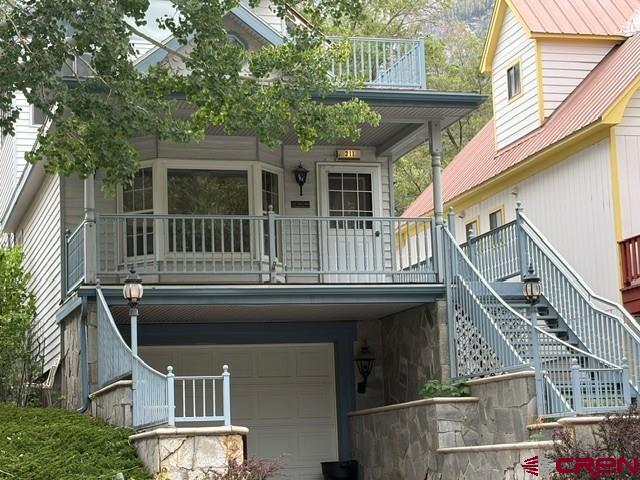 Discover a rare opportunity to create a custom mountain retreat in the very heart of Ouray, Colorado, often called the “Little San Francisco of the San Juans.” Located on the uphill side of 4th Street, just one block from the Ski Hill, this quiet and scenic property sits among some of Ouray’s most sought-after historic Victorian homes, offering a setting that perfectly blends mountain charm, walkability, and breathtaking alpine scenery.  Rooted in Ouray’s mining-era history, this unique home was thoughtfully created by blending a historic cabin with an ideal in-town building site. The result is a flexible mountain residence with duplex potential, featuring intelligently aligned entrances and stairways that allow for private, separate living spaces. Since its creation, the property has been a highly successful year-round rental, and the zoning allows long-term rentals of 30 days or more, addressing one of Ouray’s most in-demand housing needs.  Accessed via a south-side stairway, the home immediately showcases smart engineering for alpine conditions. Welded metal stairs and railings allow snow and ice to pass through, reducing winter maintenance and enhancing safety. At the top, a welcoming west-facing porch overlooks town with commanding views toward Twin Peaks and the Rock of Ages, setting the tone for the mountain lifestyle this home delivers.  From the porch, you may enter the main living level or continue to a secondary entrance—ideal for a private duplex unit or flexible multi-use living.  The lower level features a spacious great room with soaring ceilings, abundant southern windows, a bay window framing eastern mountain views, and a large private bath. The rear portion connects seamlessly to the main-level kitchen, dining, and office spaces, along with a second full bath. A back door opens to a covered rear deck, while interior stairs lead down to the full garage and workshop/studio area below.  The upper level is truly show-stopping, offering open, light-filled living with a well-sized kitchen and dining area, bedroom space, and a flexible living room. Step outside to the signature southwest-facing patio, where sweeping mountain views define the experience. The east end of this level delivers unobstructed vistas of Ouray’s famous Amphitheater, the dramatic mountain bowl above town known for its unforgettable nightly alpenglow.  The full-length lot includes a walkway to a storage area and a covered parking pad accessed from the alley—an ideal location for a future garage or potential ADU, offering additional income or guest accommodations. Parking and storage are exceptional for in-town Ouray, with on-street parking, a concrete pad, a two-car garage tucked beneath the home, and a generous workshop or studio space.  The property has been thoughtfully leveled and landscaped with perennial plantings, stone walls, and exterior lighting, reflecting the care and vision of its creators.  Due to a mid-winter leak, the upper levels have been cleared, with drywall and flooring removed. Most cabinets and fixtures are intact and ready for reinstallation, giving the next owner a rare chance to customize finishes and elevate the home to their own vision—whether modern mountain, historic restoration, or a blend of both.  Whether you’re seeking a primary residence, second or third mountain home, or a long-term rental investment near Ouray, Ridgway, Silverton, and Telluride, this property offers location, flexibility, views, and character that are increasingly rare in the San Juan Mountains.  This is your chance to own a piece of “Little San Francisco” in the Switzerland of America—where history, adventure, and alpine beauty meet.  Schedule your private showing today and imagine what’s possible.