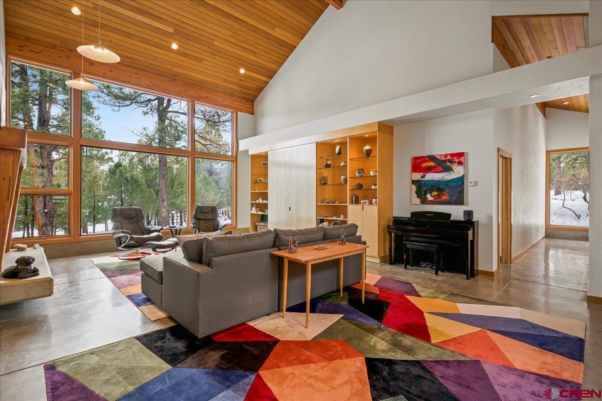 This stunning home combines mountain traditional with contemporary design, boasting an all-cedar exterior and detached over-sized 2-car garage, and welcoming front entry.  The maintenance-free interior offers a split floor plan with stained cement flooring and walls, 21' vaulted, tongue-and-groove cedar ceilings, and floor-to-ceiling picture windows framing the bucolic wooded setting, golf course views, and the various wildlife that frequently wanders through.  The grand living room has a lovely gas log fireplace for added warmth and ambiance and built-in cabinets and shelving.  A half-bath is conveniently located off the living room in the hallway leading to the primary bedroom, coat and storage closet, and laundry room on the west side of the house.  The primary bedroom suite includes a loft accessible from a metal spiral staircase providing flexible space for an office or, or other use. Flowing from the living room, the well-appointed kitchen is a chef's dream with Ceasarstone countertops, topline appliances including a convection oven and microwave and separate stovetop, pantry, and plenty of cabinetry.  The breakfast bar with a stainless steel countertop complements the ample dining area off the kitchen.  The kitchen, living room, and master bedroom all have access to the back deck among the trees overlooking the golf course with a lovely walking path to the fairway.  Off the kitchen on the east side of the home, down a few, short steps you will find the mechanics room, a large, well-equipped media room with all the necessary electronics, big screen, theater seating, and bar with storage cabinets.  Further down the hall there is another bathroom and the 2nd bedroom with an adjoining flex room, currently used as a fitness room, with a door to the outdoor patio.  This nicely landscaped, wooded, private lot is cleared for fire mitigation and offers indirect views of mountain peaks and easy access to the golf course at Tee Box No. 2.  Divide Ranch and Club offers one of the most spectacular and challenging golf courses in the country, surrounded by the beautiful San Juan Mountains and located an easy 15-minute drive to the town of Ridgway, or less than an hour from the world-renowned ski resort of Telluride, the Jeeping capital and historic mining town of Ouray, and the commercial hub and airport of Montrose.  This unique and turn-key mountain hideaway makes for a perfect permanent residence or second, seasonal home for the discerning homebuyer.  Don't pass up this opportunity to make it yours today!