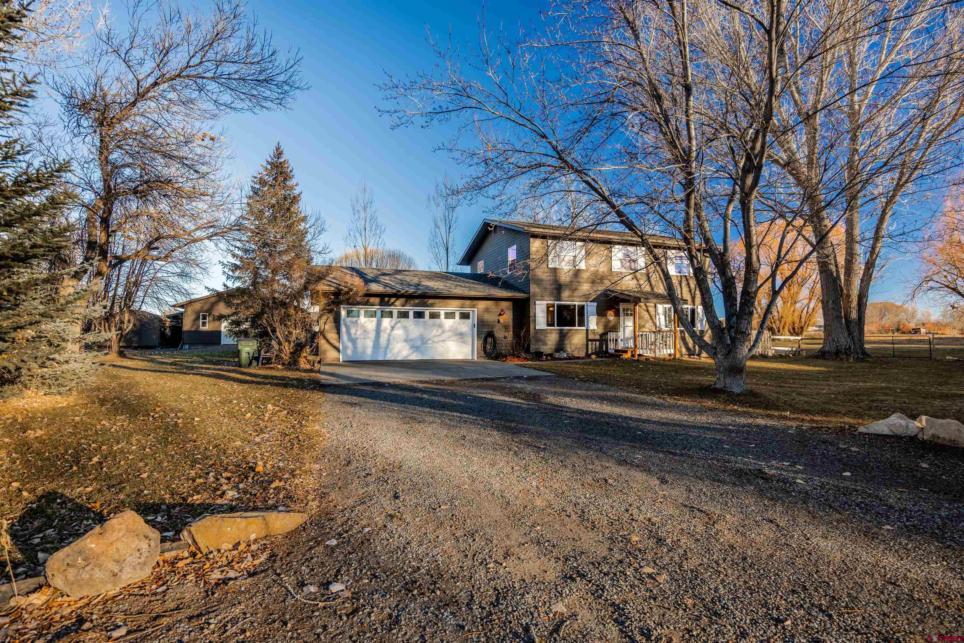 This Spring Creek property is the kind of home that’s truly hard to come by in Montrose. Set on 1.13 acres in one of the area’s most sought-after locations, it offers SPACE, PRIVACY, BREATHTAKING VIEWS, and a level of thoughtful updating that truly sets it apart.  The home has been comprehensively remodeled with intention and care. The floor plan was redesigned from four bedrooms to three, creating a spacious and serene primary suite featuring 16-foot south-facing windows that flood the room with natural light and frame incredible mountain scenery. A custom walk-in closet completes the retreat. Throughout the home, you’ll find solid core bedroom doors, new door hardware, all new windows, updated wood trim and baseboards, remodeled bathrooms, new countertops, updated appliances, and refreshed lighting and ceiling fans in every room. Popcorn ceilings were removed for a clean, modern finish, and the living room is anchored by an impressive 12-foot floor-to-ceiling window and patio door that bring the outdoors in.  The views are nothing short of exceptional. Enjoy sweeping, unobstructed vistas of the San Juan Mountains, Cimarrons, Horsefly Peak, and surrounding landscapes—a constantly changing backdrop that delivers stunning sunrises, glowing alpenglow, and peaceful evenings. Whether inside or out, the scenery is a defining feature of this home.  Outdoor living is equally impressive. A large Trex deck and expansive flagstone patio create ideal spaces for entertaining, relaxing, or simply soaking in the views. The property offers natural shade throughout the day in the summer, making outdoor enjoyment comfortable even during warmer months, while mature landscaping enhances privacy and beauty.  The shop has been fully finished with insulated walls and attic, wallboard, proper ventilation, and a pellet stove—perfect for projects, hobbies, or additional workspace year-round. A welcoming front porch and new front door add curb appeal, while extensive landscaping improvements include trees, fencing, grasses, and wildflowers. Leaf-block gutters and full fencing complete the exterior.  Major system upgrades add long-term value and comfort. The home is heated with high-efficiency hot water baseboard heat, providing consistent, cozy warmth throughout the winter months. Additional improvements include crawlspace encapsulation and an evaporative cooler, contributing to the home’s impressive energy efficiency. Naturally cool and shaded in the summer, the home also benefits from winter sun that helps warm the interior on clear days. Additional features include an oversized heated garage, a loafing shed ideal for hobby farm use, and multiple storage sheds—offering exceptional flexibility and storage options.  This is a RARE Spring Creek offering that seamlessly blends land, jaw-dropping views, functionality, efficiency, and timeless upgrades—perfect for buyers seeking a home that has been genuinely cared for and thoughtfully improved.