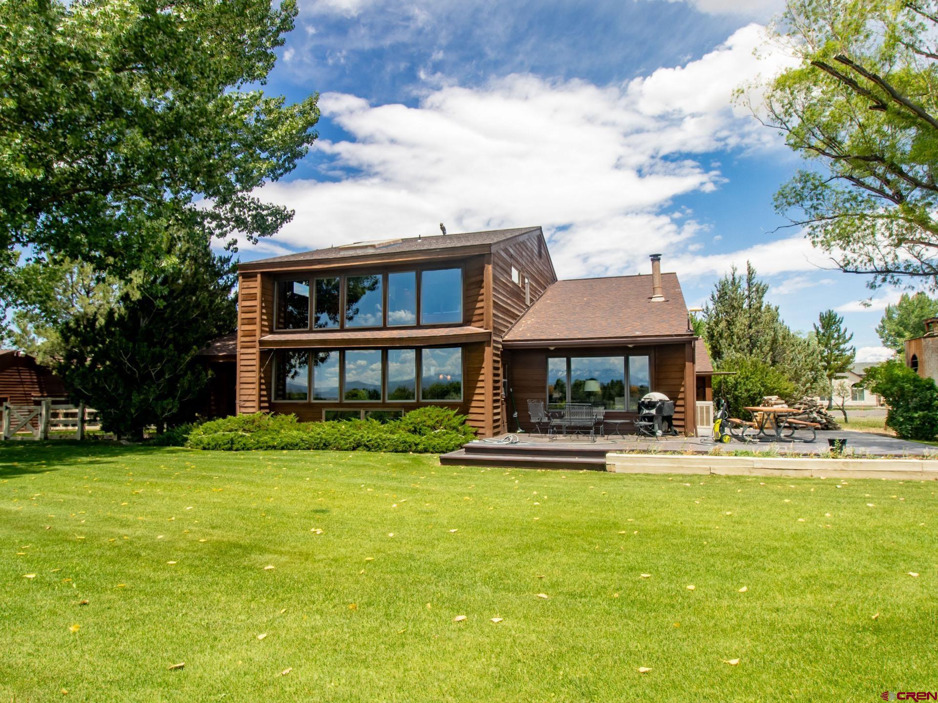 Experience the perfect blend of privacy, space, and stunning mountain views on this beautifully maintained 0.87-acre property tucked away at the end of a quiet cul-de-sac. With irrigation water, room for animals, deluxe RV storage, and breathtaking San Juan Mountain vistas, this property offers the lifestyle many Western Colorado buyers dream of. Designed by local professional architecture Patrick Davis to maximize big views, passive solar efficiency, and timeless exterior design, this 4-bedroom, 3-bath home features soaring ceilings and an open-concept design that creates a brightly sunlit and welcoming atmosphere. The living room, dining area, and kitchen flow seamlessly together, anchored by a cozy woodburning stove, custom oak built-ins, and handsome hardwood flooring throughout key living spaces. The sunroom serves as a year-round retreat with soaring ceilings, expansive windows, slate-tile flooring, and a hot tub perfectly positioned to capture the surrounding views. Step outside to a spacious private deck with panoramic views, a large backyard, and mature landscaping. Beyond the home, the property truly shines. A two-car attached garage is complemented by an approximately 615-square-foot detached RV garage with electricity, providing exceptional storage for recreational vehicles and toys or doubling as a workshop. An additional outbuilding offers flexibility for horses, equipment storage, or hobby farm pursuits. A brand-new roof on the home with warranty transfer brings added confidence. Whether you're seeking room to roam, a place for your toys and animals, or simply a peaceful setting with unforgettable views, this unique property delivers the space, functionality, and lifestyle opportunities with endless possibilities.
