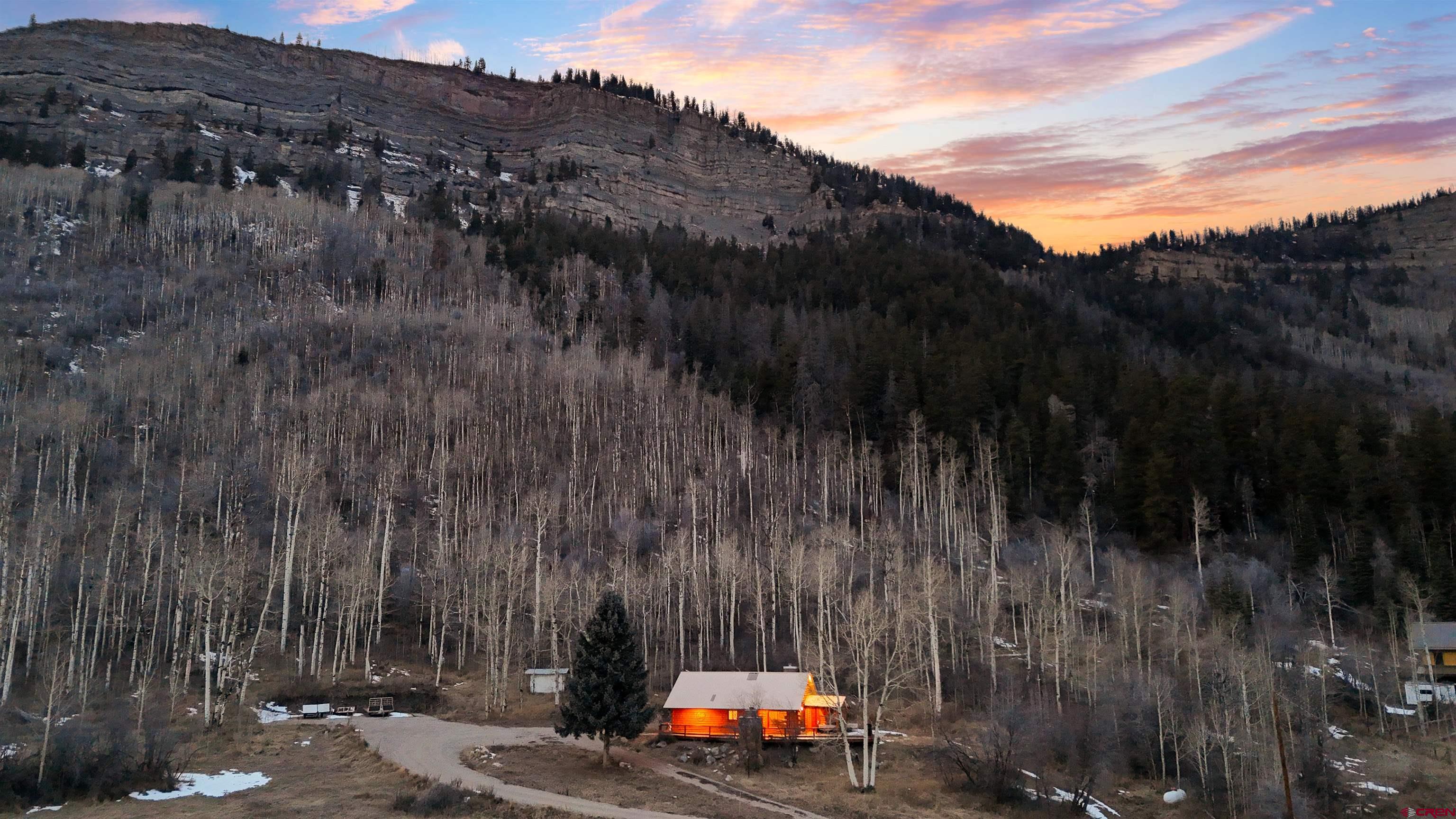 There is a reason North Animas Valley living is among the most sought-after locations in Durango, Colorado. Proximity to the San Juan National Forest, sweeping valley views, dramatic red cliffs, and access to world-class golf and winter recreation define this exceptional setting. At this property, those lifestyle advantages are taken even further. Twelve private acres back directly into the San Juan National Forest, creating an unforgettable high-alpine backdrop with privacy, views, and immediate access to outdoor adventure. The premium parcel is improved with a fully remodeled luxury cabin featuring modern upgrades and high-end fit and finish. With no HOA and no covenants, the opportunities here are vast. Renovated from top to bottom in 2022, the 1,550 square foot mountain home is warm, inviting, and move-in ready. The interior offers two bedrooms plus a large bonus flex room, ideal for a bunk room, office, gear room, or additional sleeping space. An open-concept main living area is anchored by a stone fireplace and complemented by vaulted ceilings, abundant natural light, and tile flooring designed to resemble wood while offering durability and easy maintenance. The kitchen flows seamlessly into the living and dining areas and features granite countertops, updated cabinetry, and a layout designed for entertaining after a day in the mountains. A renovated full bathroom and main-level laundry provide comfort and convenience for year-round living. Outdoor living truly sets this property apart. A low-maintenance composite deck creates the perfect space for gathering, complete with an exterior fireplace ideal for morning coffee, sunset dinners, and star-filled nights overlooking the valley, with the San Juan Mountains as the backdrop. There is ample parking for toys, trailers, RVs, motorhomes, and off-road vehicles, making this property exceptionally well-suited for an adventure-driven lifestyle. With multiple potential building sites, the land also offers long-term versatility. Build a primary residence while keeping the cabin as a guest house, create a multi-structure mountain compound, or explore future development options through La Plata County planning. The property is zoned Large Lot Residential with a three-acre minimum lot size, with any subdivision subject to county approval. Practical features include a domestic well, septic system, LPEA electric service, propane baseboard heat, a durable metal roof, and a built-in backup generator, a valuable upgrade for mountain reliability. Located just 25 minutes from downtown Durango, this property offers both seclusion and convenience. Whether you are searching for a mountain cabin, a Colorado retreat on acreage, a no-HOA property, or a potential short-term rental near Purgatory, The King Cabin delivers the setting, lifestyle, and flexibility today’s buyers are seeking.