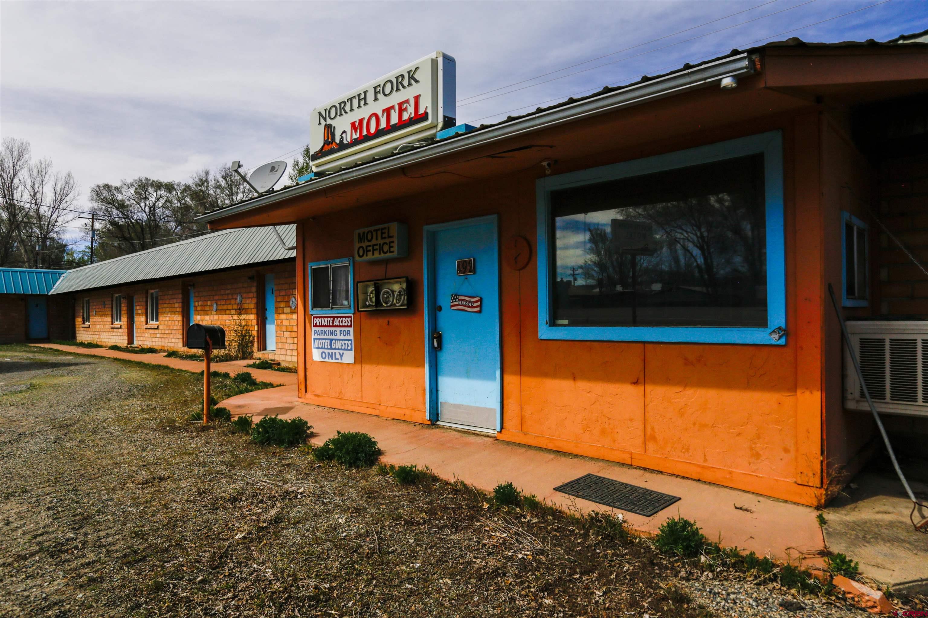 Prime location at the heart of Hotchkiss — a rare commercial opportunity situated at the Y where CO Highway 92 meets Highway 133, on the north side of the highways with excellent visibility and easy access. Known locally as the “Old North Fork Motel,” the property features a main building with six motel units (each with a full bath and two with small kitchens, with Units 5 and 6 connected by an interior door) plus a generous manager’s one-bedroom apartment/office that includes a full kitchen, full bath, large living room, laundry room and reception/office area, and a chain-link fenced backyard. The motel building is approximately 2,402 sq. ft. (including the office/reception) and the apartment is about 1,315 sq. ft. The property has been approved by the town of Hotchkiss for mixed-use. This high-traffic, well-known location is a standout investment in town.