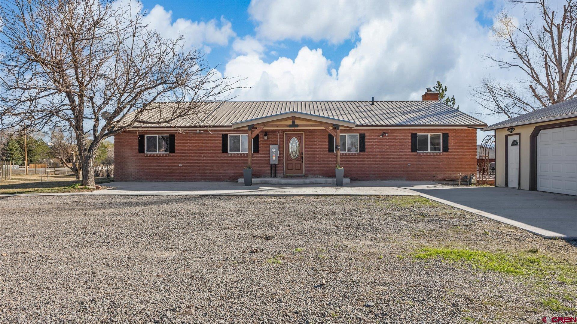 Live the Dream in a Beautiful, Ranch Level Brick Home with a Detached Shop, Irrigation Water and No Hoa on 3+ Acres! All of this in an ideal location that delivers that peaceful, tranquil environment while being minutes from all the best amenities Montrose has to offer. A sprawling, lush property with fruit trees, views, and all sorts of extra space to expand and create, this property is teaming with potential. Step inside to a warm, inviting home filled with character, and delivering an open concept floor plan. Get the kitchen you've always dreamed of with tons of counter space and cabinet storage, an ergonomic layout, and plenty of room to customize and make it your own. The dining and living rooms are spacious and will accommodate your loved ones with ease, and feature custom touches such as wood beam work, built-ins, and a massive wood stove. A large laundry room allows you to keep the mess out of sight, and includes extra storage and access to the backyard. The en-suite is perfect for someone looking for extra space and flexibility, with room to accommodate a home office, reading nook or yoga mat. Step outside and enjoy all the freedom and flexibility in the world with a detached shop garage, which has power and is insulated. With a new roof, a riding lawn mower, and tons of space to tinker, this is the perfect space to house your hobbies. Sit on your massive back deck sipping your favorite beverage watching the sunset in complete privacy. Wander through lush orchards, pick an apple off your own tree, and let the stress of life dissipate with the unmatched tranquility of your new home. Amenities like this typically require a 15+ minute commute out of town. With the incredible benefit of no HOA or covenants, allowing you to let freedom reign, and the added benefit of being in the county and not the city, allowing you to save money, is this even a decision? Secure Your Slice of Paradise with This Exceptional and Rare Property, Experience it For Yourself Today!