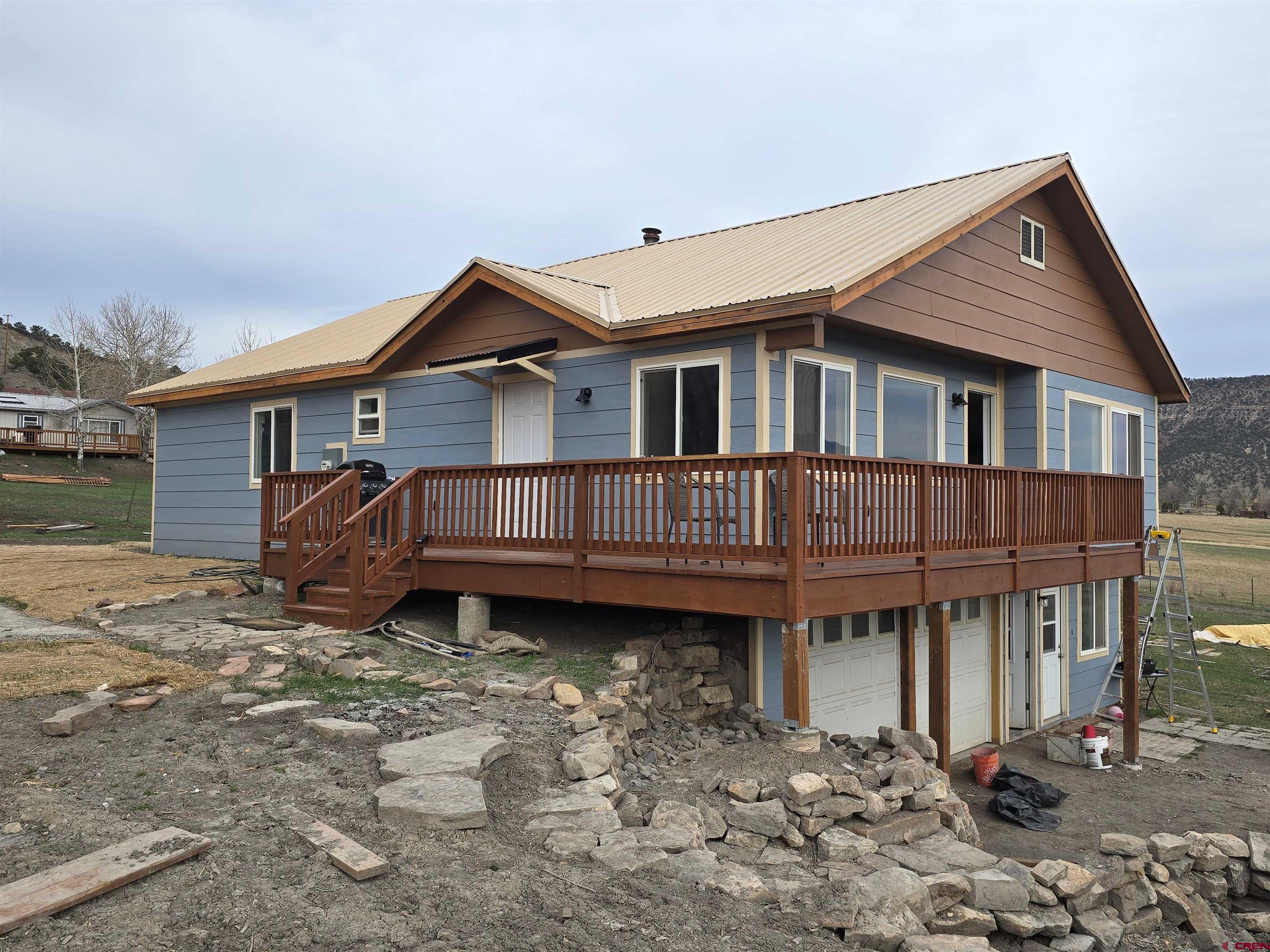 Great location in Ridgway with beautiful views of the valley and walk onto the balcony for breath taking views of the San Juans and Cimarron ranges.  A Cozy 3 bedroom, 3 bathroom home. The great room has plenty of windows to let in the morning sun. The wood burning insert (EPA approved) adds ambience .  The Kitchen has been remodled and updated with stainless steel appliances and granite countertops. The gas stove allows for fast and efficient cooking. The recently added island has seating for ease and convenience.  The windows are vinyl with double panes for higher efficiency. The Primary bedroom suite has a newly updated bathroom. The main floor bathroom has been recently updated and allows privacy for the other two bedrooms. The entire main level was upgraded with engineered flooring for easy care and durability. The downstairs has another 700 sq ft bonus area with a walkout door to the north and east. The laundry/utility room is on this level and the washer & dryer are staying. The lower level has its own full bath. The oversized garage (500+sf) enters directly into the house making it easy to stay warm in the winter. Directly off the garage is another large bonus area perfect for your shop or convert it into something special. The exterior siding was replaced last year. The 1/2 acre lot has plenty of room for your needs.  There are NO Covenants and NO HOA.  Professional photos on 4/17/26.