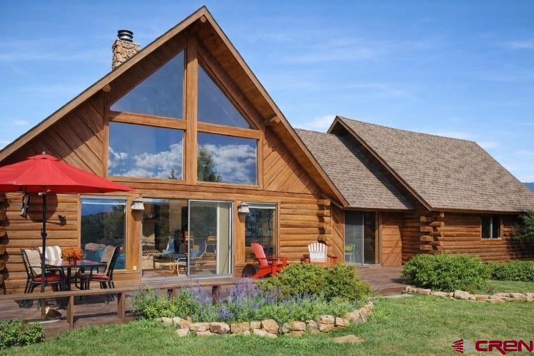 Welcome to your Colorado mountain retreat in the heart of Log Hill Village, in the Township of Ridgway, one of Ouray County’s most sought-after communities. This custom-crafted log home sits on a sun-soaked knoll with sweeping views of the Sneffels Range and surrounding peaks. Here, you’ll experience the perfect balance of rustic character, modern comfort, and unbeatable access to all the San Juan lifestyle offers.  Step inside and be greeted by a dramatic great room with towering ceilings and floor-to-ceiling windows, designed to frame the mountain views and fill the space with natural light. A classic stone fireplace anchors the room, creating a warm gathering space that flows easily into a spacious dining area—perfect as is or ideal for conversion into an additional bedroom or entertainment space. The central kitchen is conveniently placed, while two comfortable guest bedrooms and a full bath round out the main level. Step onto the large south-facing deck to enjoy year-round sunshine, mountain air, and the sight of deer and wild turkeys wandering across your property.  Upstairs, the private primary suite offers its own full bath and a deck with panoramic views that stretch from the Grand Mesa to the Cimarrons to Horsefly Peak. Morning coffee or evening stargazing here will quickly become your favorite rituals. The oversized log-crafted garage with vaulted ceilings offers incredible flexibility—already beautiful for vehicles, but easily adaptable into additional living space or even a loft.  Life in Log Hill Village means endless opportunities for adventure and relaxation. From here, you’re just 5 minutes walk to the Mesa's rim with amazing views and 10 minutes to Divide Ranch & Club. Take daily hikes on nearby trails like the scenic Escarpment Path, ride your e-bike on quiet country roads, or soak in natural hot springs after a day on the slopes. Festivals, outdoor concerts in the Ridgway park, fine dining, and friendly neighbors make this an unbeatable year-round or seasonal retreat.  The airport in Montrose is about 45 minutes away.  Offered fully furnished and move-in ready, this special property is more than a home—it’s a mountain lifestyle waiting for you.