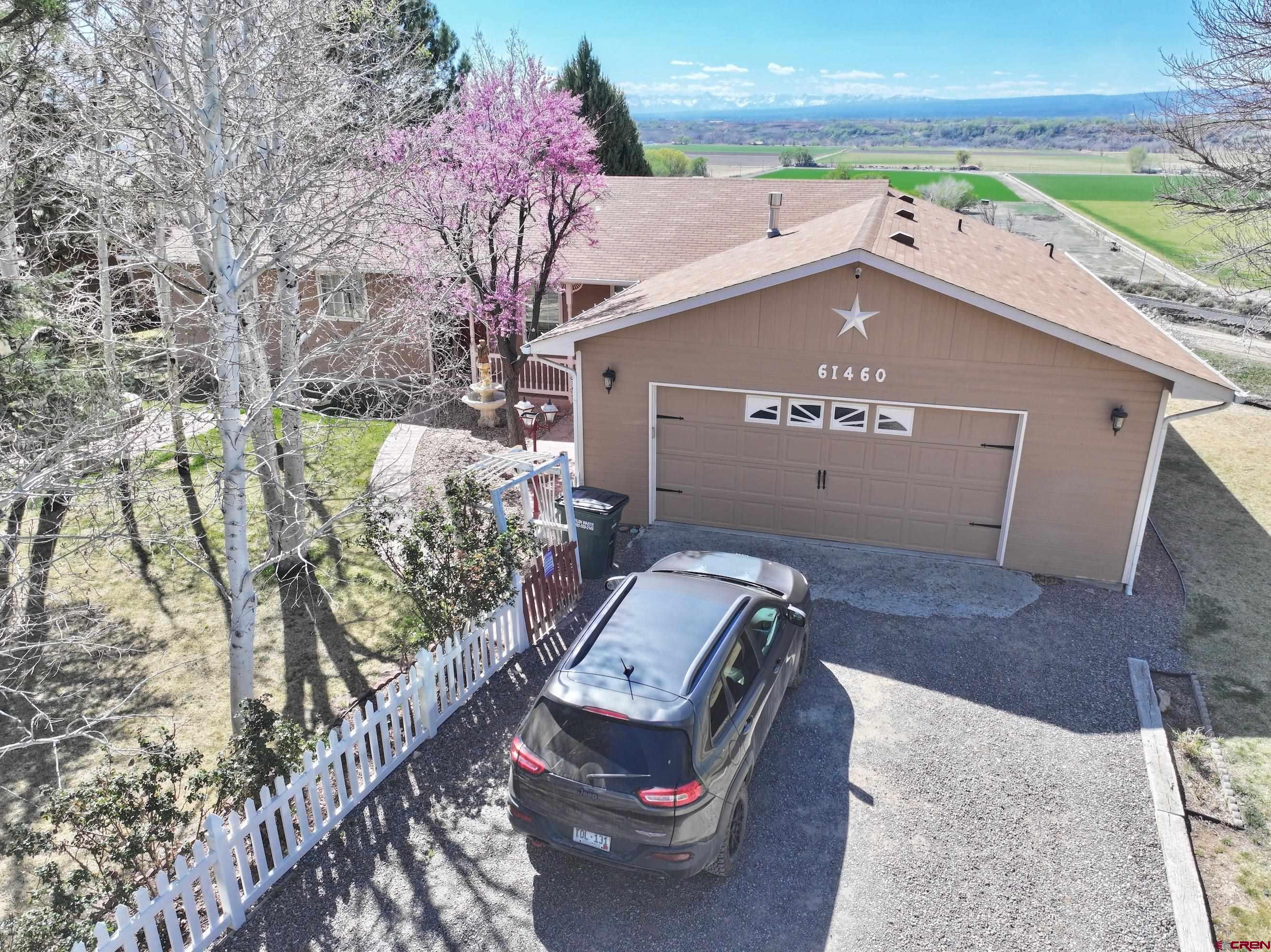 Perched along the edge of the hillside, this exceptional property captures sweeping, unobstructed views of the San Juan Mountains and the twinkling city lights below—an unforgettable backdrop for refined Colorado living. Ideally situated just minutes from Montrose, yet tucked within a quiet and highly sought-after neighborhood with irrigation water, this residence offers the perfect balance of convenience and serenity. Thoughtfully designed for both comfort and ease, the home features a low-maintenance layout with three bedrooms and two baths, complemented by a two-car attached garage. A rare and valuable addition is the expansive detached two-car garage—ideal for a workshop, fitness studio, or hobby space—along with a storage shed and a finished “fun shed” that invites creativity or relaxation. Inside, the home has been tastefully updated and impeccably maintained. The primary suite is a true retreat, showcasing a beautifully remodeled bath with an elegant tiled walk-in shower and a generous walk-in closet. The kitchen is equally impressive, offering stylish countertops, abundant custom cabinetry, a pantry, and seamless access to the back deck. Step outside to experience quintessential Western Colorado living—lush, thoughtfully curated landscaping provides shade, privacy, and year-round beauty. The expansive deck is perfectly positioned to take in vibrant sunsets, panoramic mountain vistas, and the sparkling lights of the valley below. Immaculate, inviting, and rich with both functionality and charm, this is a rare opportunity to own a home where every detail has been carefully considered and every view leaves a lasting impression.