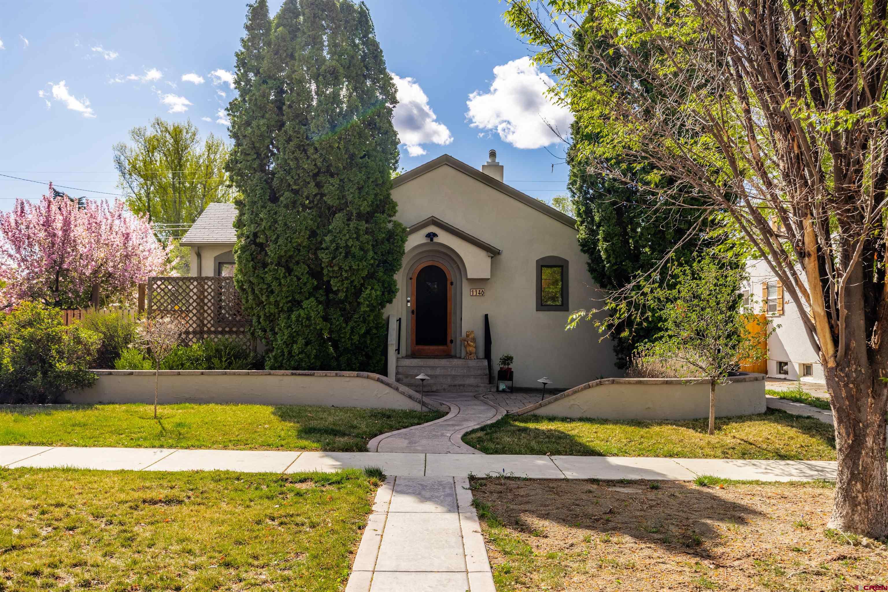 Timeless 1930s character meets elevated modern living in this exquisitely reimagined bungalow, ideally situated in the heart of downtown Montrose.  Offering 2,196 square feet of thoughtfully designed living space, this residence showcases a seamless blend of historic charm and upscale finishes. The main level features a desirable primary suite, creating a private and convenient retreat, while expansive living areas are filled with natural light and anchored by warm, inviting tones and refined details throughout.  The beautifully updated kitchen is both functional and sophisticated, complemented by custom cabinetry, quality appliances, and an open-concept flow ideal for entertaining. The living room, complete with a wood-burning fireplace, transitions effortlessly into additional flex living space, perfect for a den, office, or media area.  The lower level expands the home’s versatility, offering two additional bedrooms, a dedicated laundry area, workshop space, and ample storage—ideal for guests, hobbies, or multi-functional living.  Set on three city lots, the outdoor environment is a rare and exceptional offering. Designed with privacy and year-round enjoyment in mind, the grounds provide abundant space for entertaining, gardening, or simply enjoying Colorado’s natural beauty.  Additional features include a one-car garage and an attached two-car carport, ensuring ample parking and convenience.  Located just moments from downtown amenities, dining, and medical services including Montrose Regional Health, this property delivers both lifestyle and location.  A truly distinctive offering—where classic architecture, modern comfort, and exceptional outdoor space come together in one remarkable home.