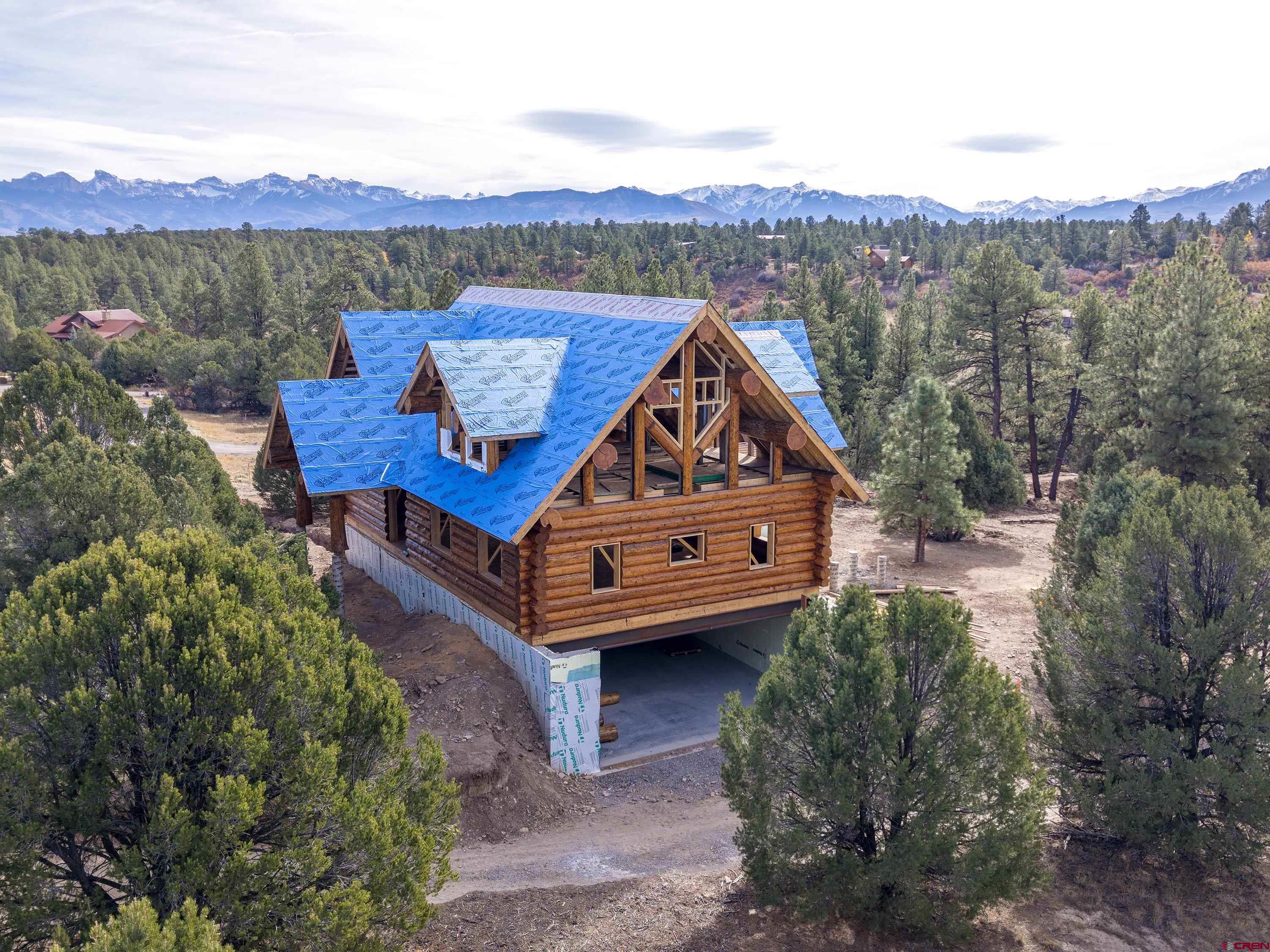 Scheduled for completion in summer of 2026! Situated on a quiet cul de sac close to the Divide Ranch golf course on Loghill Mesa, 74 White Tail Lane is only a short drive from the thriving town of Ridgway, Colorado. The tree-covered, flat lot offers expansive mountain views of Mount Sneffels and the San Juan Mountain Range. The open-concept, sun-soaked log home exceeds 5,000 square feet and features rare western cedar from Idaho. The multi-level layout features a loft, alcove, workshop, and a 946-square-foot garage. Additionally, the home boasts 659 square feet of decks, including a private deck off the master bedroom.  There is a bath in the cellar with a shower and a plumbed dog washing station.  There is the potential for 5 bedrooms, 4 downstairs with a master upstairs, which would require enlargement of the leach field and a change in the plumbing plan, along with the possibility of County approval.