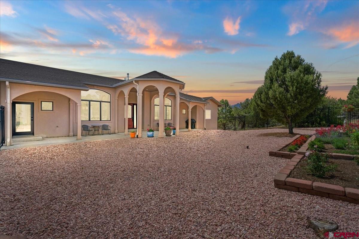 In the heart of Ridgway and Ouray County, where the dramatic peaks of the Sneffels Range and the rugged beauty of the Cimarron Mountains define the skyline, “Waterview” stands as one of Southwest Colorado’s most exceptional luxury residences. Set along a rare escarpment above Ridgway Reservoir and overlooking Ridgway State Park, this home captures an unmatched combination of mountain, water, and open-space views—an increasingly rare offering in today’s luxury real estate market.  This custom-designed residence was thoughtfully crafted by local master builders to maximize both comfort and scenery. Every angle of the home was intentionally positioned to frame panoramic views of snowcapped peaks, alpine waters, and wide-open Colorado skies. Whether you are searching for a full-time residence, a mountain retreat, or a high-end seasonal escape, this property delivers the ideal blend of privacy, functionality, and elevated mountain living.  Arriving at the home, you are welcomed by a private, tree-lined approach leading to a grand yet secluded entry. A fenced courtyard helps protect landscaping and gardens from local wildlife, while the covered entry creates a warm and inviting arrival experience. Outdoor seating areas capture direct views of Mount Sneffels, offering a peaceful place to enjoy sunrise coffee or evening alpenglow.  Inside, the home features soaring ceilings, rich custom finishes, and a flowing open-concept layout designed for both everyday living and entertaining. The great room anchors the main level, seamlessly connecting to expansive view-facing windows and multiple access points to the outdoor Trex deck. The setting is ideal for year-round enjoyment—summer sunsets over the reservoir, fall colors in the valleys, and snow-covered peaks in winter.  The gourmet kitchen is a true centerpiece, featuring a large island oriented toward the mountains, premium stainless appliances, and extensive custom cabinetry with pull-out storage. Adjacent dining spaces offer flexibility, from casual breakfast nooks framed by floor-to-ceiling windows to a more formal dining room filled with natural western light and detailed tray ceilings. A striking see-through fireplace with Roman plaster accent wall adds architectural warmth and subtle separation between living spaces.  The primary suite is a private retreat with sweeping water and mountain views. The spa-inspired bath includes dual walk-in closets, separate vanities, a walk-in snail shower, and a luxurious soaking tub designed for relaxation after a day exploring the mountains.  The lower level expands the home’s livability with a spacious recreation area ideal for a media room, game space, fitness studio, or creative retreat. A custom wet bar with matching cabinetry, beverage refrigerators, and seating area makes it perfect for entertaining. Additional bedrooms and flexible rooms provide space for guests, offices, or hobbies, while large windows continue to frame the surrounding mountain and water views.  High-efficiency systems—including in-floor radiant heating, modern cooling, and quality mechanical design—ensure year-round comfort and energy efficiency. Every detail reflects thoughtful craftsmanship and long-term livability.  Beyond the home, the lifestyle is what truly sets this property apart. Minutes from Ouray, often called the “Switzerland of America,” and within reach of world-class skiing at Telluride and Telluride Ski Resort, this location offers unmatched access to adventure. Residents enjoy hiking, mountain biking, jeeping, fly fishing, and endless exploration throughout the San Juan Mountains. The nearby city of Montrose provides convenient access to shopping, dining, and regional air travel.  Waterview is more than a home—it is a rare opportunity to own a premier luxury property in one of Colorado’s most breathtaking settings. With s