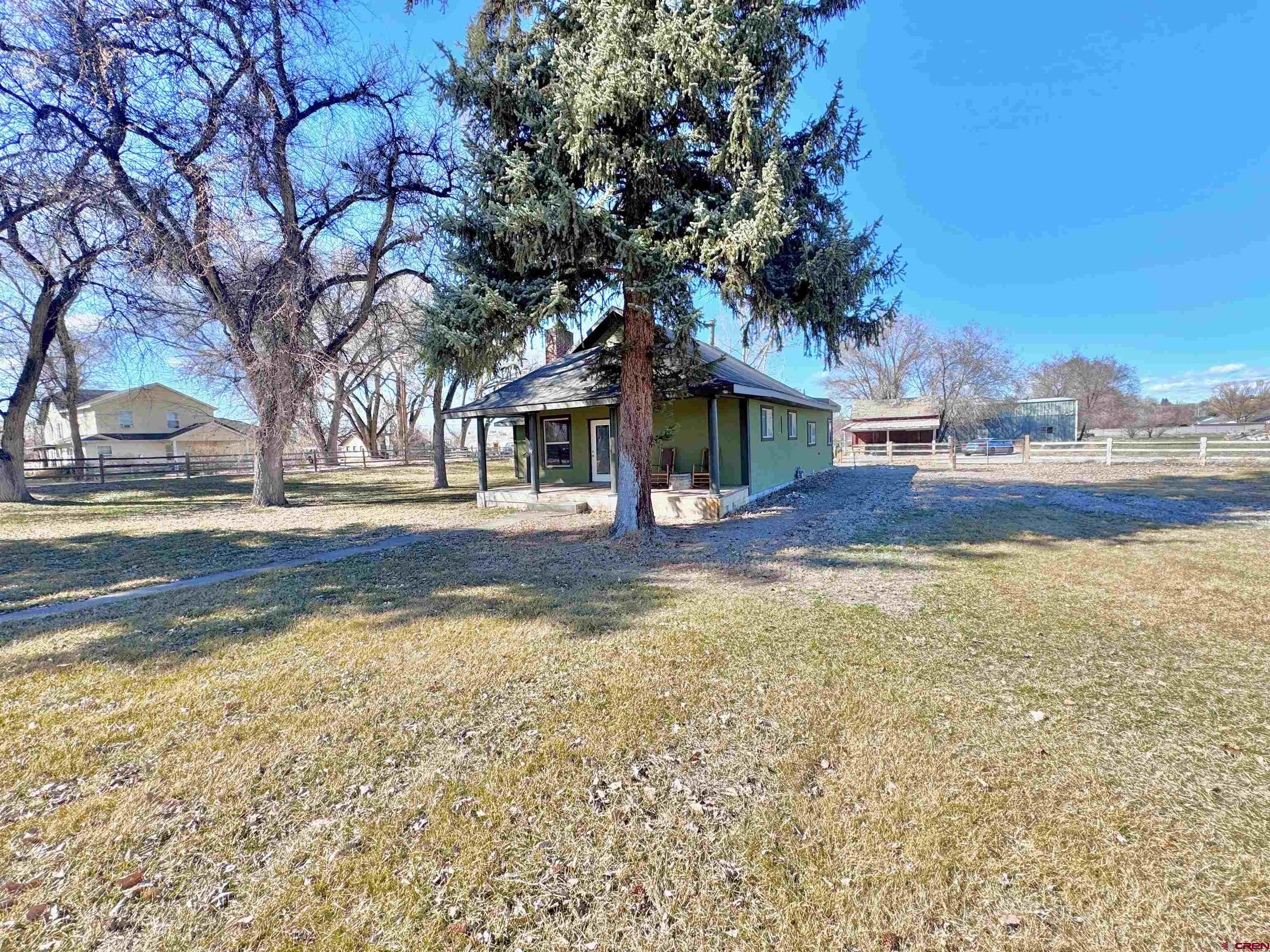 Timeless Farmhouse Elegance Meets Modern Luxury on Expansive 4-Lot Property with large shop!  Beautifully remodeled and thoughtfully designed, this exceptional farmhouse estate spans FOUR separate lots, offering a rare blend of classic charm, upscale finishes, and endless opportunity. From the moment you arrive, the inviting front porch—perfectly suited for quiet mornings in a rocking chair—sets the tone for the warmth and character found throughout.  Inside, the heart of the home is a stunning, designer kitchen featuring granite countertops, stainless steel appliances, rich custom woodwork, and a striking tin ceiling accented by exposed wood beams—creating a space that is both sophisticated and welcoming. The spacious primary suite serves as a private retreat, complete with a beautifully tiled bath designed for comfort and style.  The living room offers a cozy yet refined gathering space with a fireplace and an eye-catching loft highlighted by iron railing detail. A charming office with custom built-ins, a comfortable guest bedroom, and a well-appointed guest bath with tasteful tile finishes complete the thoughtfully designed interior.  Outdoors, the property truly shines. Lush lawn, mature trees, and classic split rail fencing create a peaceful, park-like setting, while additional improvements include a large storage shed with covered space for added functionality.  For those seeking versatility and freedom, this property delivers. The impressive shop—complete with power, concrete flooring, built-in workbench, dedicated office/storage room, and oversized overhead doors—offers endless possibilities for hobbies, equipment, or workspace needs. With no covenants, irrigation water, and four separate lots, this is a rare opportunity to expand, build, or simply enjoy the space as your own private retreat.  Bring your vision, your toys, and your Colorado lifestyle dreams—this one-of-a-kind property is ready to deliver.  Buyer to verify any additional water tap, sewer tap, gas, and power availability and pricing.