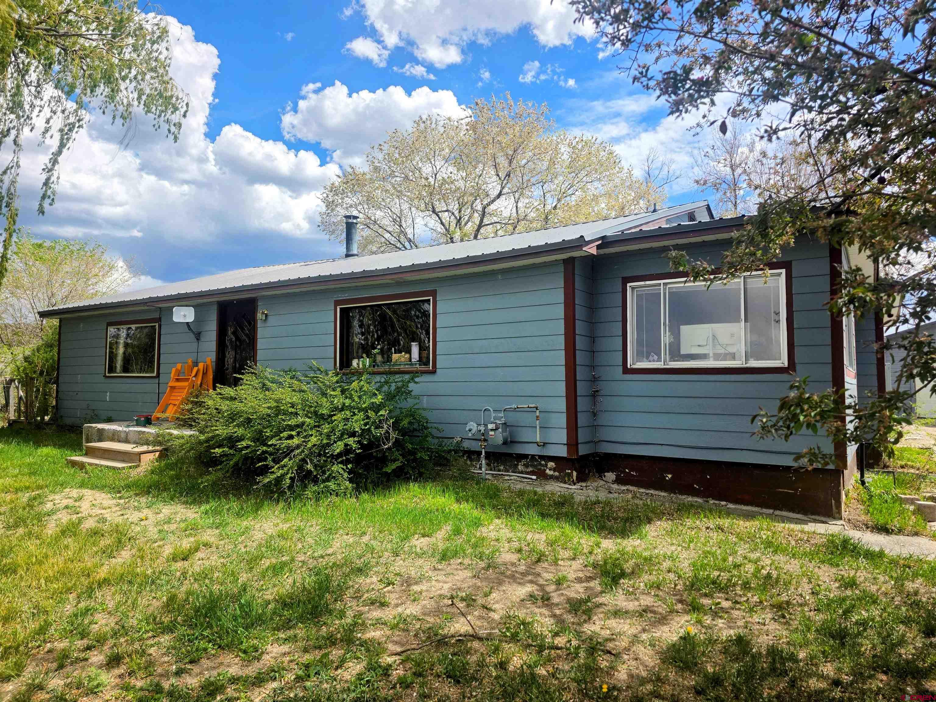 This 3.63-acre property includes 4.3 shares of irrigation water that is shared with just one neighbor.  The 2,440 sq.ft. home, originally built in 1955, carries the charm of its era while offering generous living spaces and practical updates. Inside, you’ll find 3 bedrooms and 2 bathrooms, 2 large living areas, and a layout that feels welcoming from the moment you step in.  There is also the capability of having an ADU.  The east side of the house has a +/- 563 sq.ft. room that can be locked off from the rest of the dwelling.  It has a separate entrance, a bathroom (one of the two bathrooms in the house), a kitchenette and a large living room.  A detached 2-car garage provides everyday convenience, but the real standout is the impressive +/- 1,870 sq.ft. shop, complete with a large storage mezzanine and a composting toilet. Whether you’re a craftsman, mechanic, hobbyist, or need serious storage, this shop delivers!!  With a convenient rural location with quick access to town, this is the kind of property that rarely comes available—land, water, a solid home, and an exceptional outbuilding all in one package. Perfect for those who want space to spread out without sacrificing convenience.