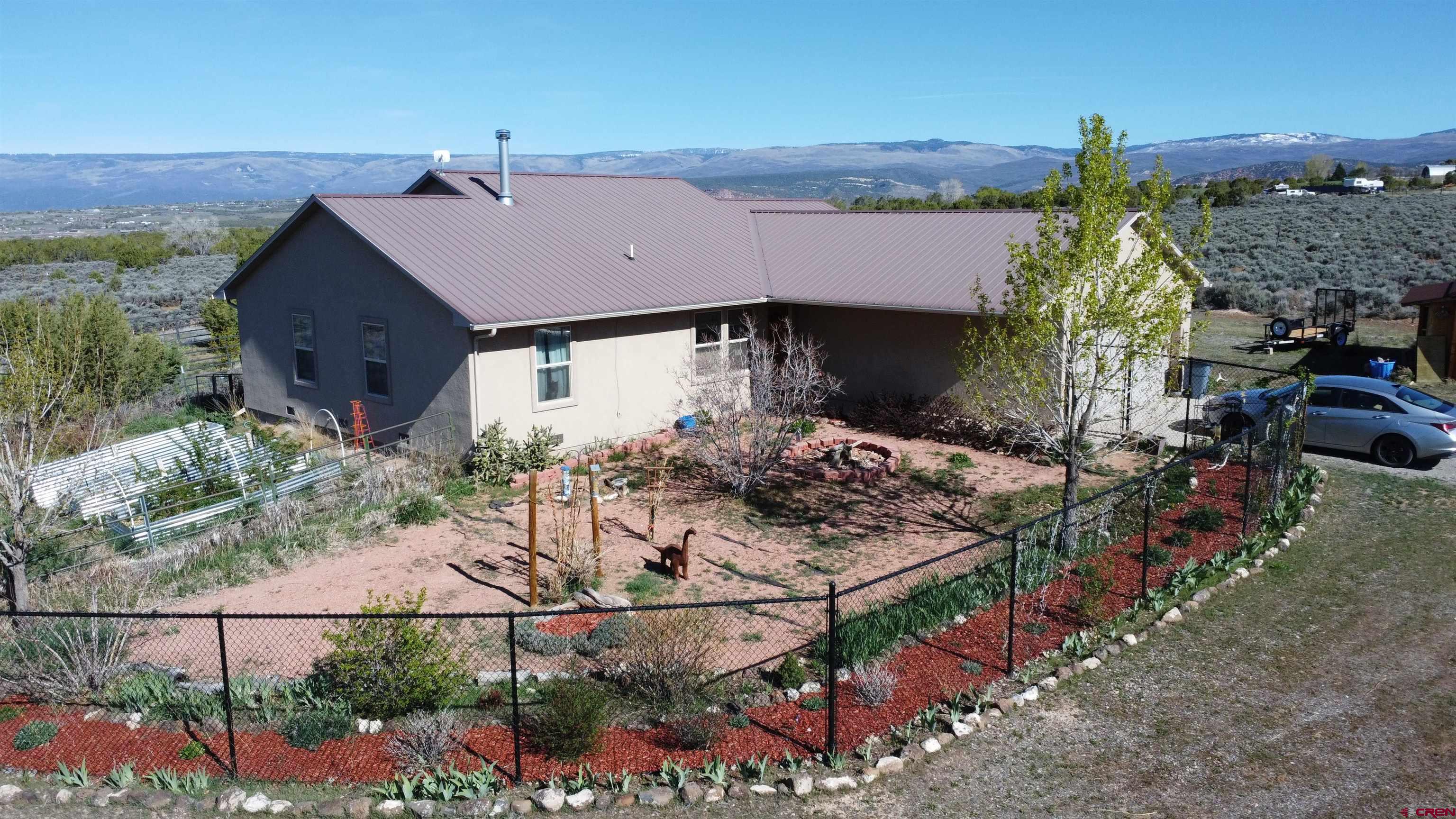 Stunning ranch home on 9.75 acres with 360 degree views!  This 3 bed/2bath home boasts a split bedroom design with spacious rooms, huge primary suite with walk-in closet, tiled shower, and a separate soaker tub.  Beautiful tongue and groove Beatle kill pine ceiling, open living/dining area, a quaint antique wood fired stove heats the home along with the forced air heat in the winter months, while the central A/C keeps the home comfortable in the summer.   Attached 2 car garage, stucco siding, metal roof, and so much more.  The house is beautiful but pales in comparison to the views.  The setting is amazing, and the views are even better.  You can see the Uncompahgre, the Grand Mesa, the Gunnison Gorge, West Elk Mountain Range, and the San Juans!  On 9.75 acres you have enough elbow room from the neighbors.  The property includes multiple outbuildings with a 2 stall barn with tack and feed room, shed to park your toys in, and a garden shed.  Raised garden beds, a fenced in orchard, and powder coated chain link fence are just the icing on the cake.  You are going to want to look at this one.