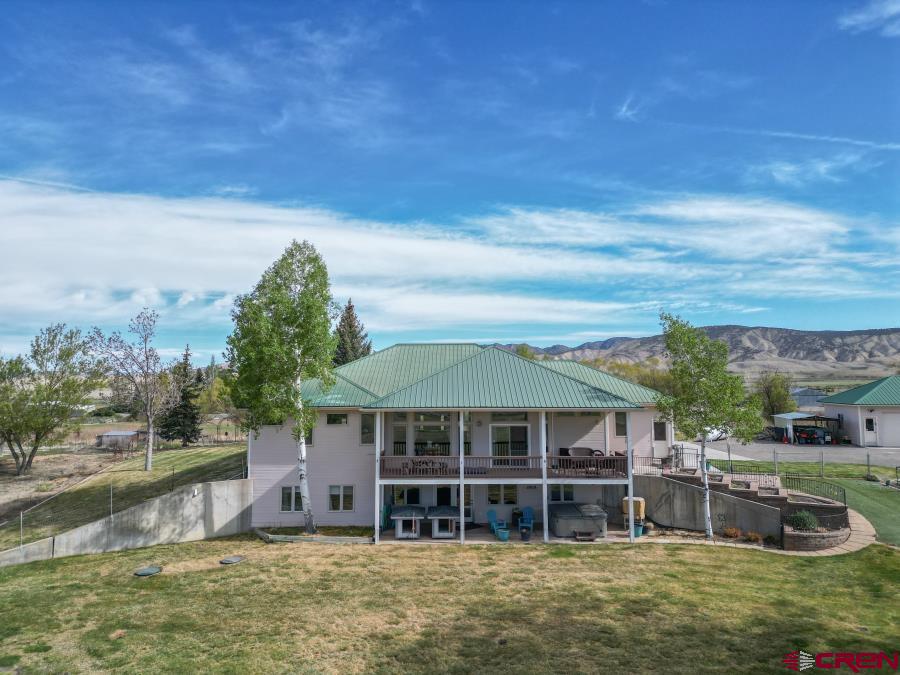 Where Views, Privacy & Family Living Come Together-  Wake up to breathtaking snowcapped mountain views in the winter. Enjoy peaceful hay fields, grazing cattle, soaring eagles, and passing deer —all from your own private deck. On 4.8 acres of irrigated land, bring your toys, your horses, your chickens, your hobbies… or just enjoy the peace and quiet.  With over 3500 square feet of finished square footage and anther 288 of storage space, this spacious home was designed for gatherings. From summer barbecues to unforgettable Holiday dinners, there’s room for everyone. The beautiful kitchen serves as the heart of the home, naturally drawing friends and family together, while the expansive living spaces create comfort and connection year-round. The Primary suite is a true retreat, with a large walk-in shower and an extra-large soaking tub.  The laundry room is oversized, with tons of cabinets for gear and a big utility sink—great for projects, or muddy puppy paws.  Step outside and experience true Colorado living—You'll  enjoy quiet nights by the fire pit, listening to the crackle of the flames while looking at the stars in the dark country sky. Host the Fourth of July fireworks celebrations. Start your serene mornings soaking in the hot tub with nothing but sounds of birds and sprinklers and the smell of fresh air.  The property offers exceptional privacy with a private drive, fenced yard, and plenty of space for kids, grandkids, and pets to roam safely. A greenhouse provides the opportunity for homegrown vegetables and herbs, adding to the self-sufficient, country-lifestyle feel.  One of the nicest features are the large windows which fill the home with natural light and warmth. The a large living room with 9' foot ceilings which flow into the dining room on the main level. The lower level includes a very spacious bedroom, a well appointment bathroom with custom walk-in shower, plus the media space all in the walk-out basement.  You have all the additional living space you may need, which makes it perfect  for extended family or guests to stay comfortably.  You will never run out of storage space with the attached 3 car garage which has a tall door on one end, the detached 4 car garage,  plus large covered parking area.  If you’ve been looking for a place that offers space, views that will stop you in your tracks, privacy, and a true sense of home—this is it. All just minutes from Town!  Homes like this don’t come along often so set up your showing soon!