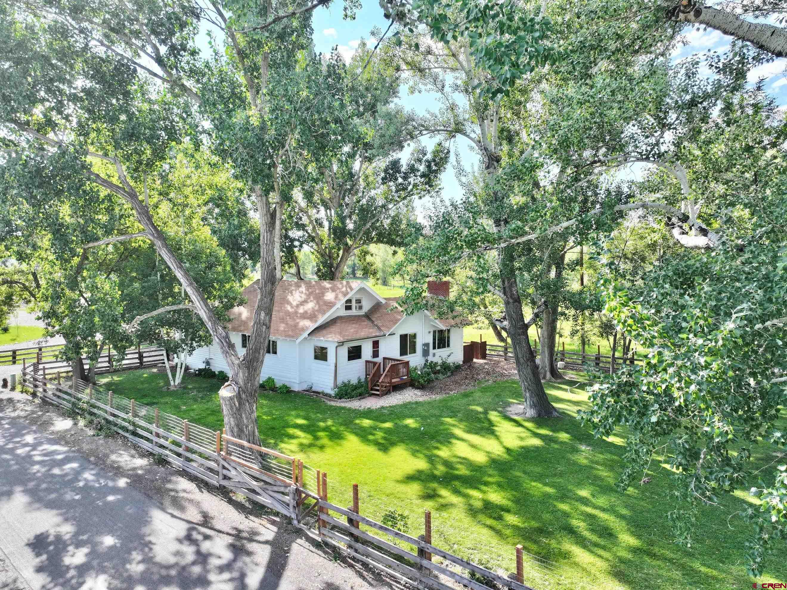 Old farmhouse offering three bedrooms and two baths, nestled on 7.4 acres of lush land with a thoughtfully designed horse setup. Positioned in coveted south Montrose, this residence enjoys convenient proximity to shopping, dining, and the newly established community recreation center. Enveloped by prestigious subdivisions, it proudly possesses 4.7 shares of UVWUA irrigation water and a captivating rolling pasture.  The farmhouse boasts an upgraded electrical panel, new central air conditioning, revamped plumbing infrastructure, and carefully trimmed large trees. Nearly all windows have been replaced. This enchanting property beckons you to bring your toys or livestock, featuring amenities such as a 3-run loafing shed with 2 waterers, a tack shed, a spacious workshop, a newer chicken coop, and a detached two-car garage. Approach the home through paved roads, bordered by stately trees and charming split rail fencing.  Convenience takes precedence with a mudroom off the eastern entrance, complete with a washer and dryer closet, and a separate entryway on the west side of the home. This farmhouse masterfully combines timeless appeal with contemporary comforts. Take a look at this treasure of a property today!