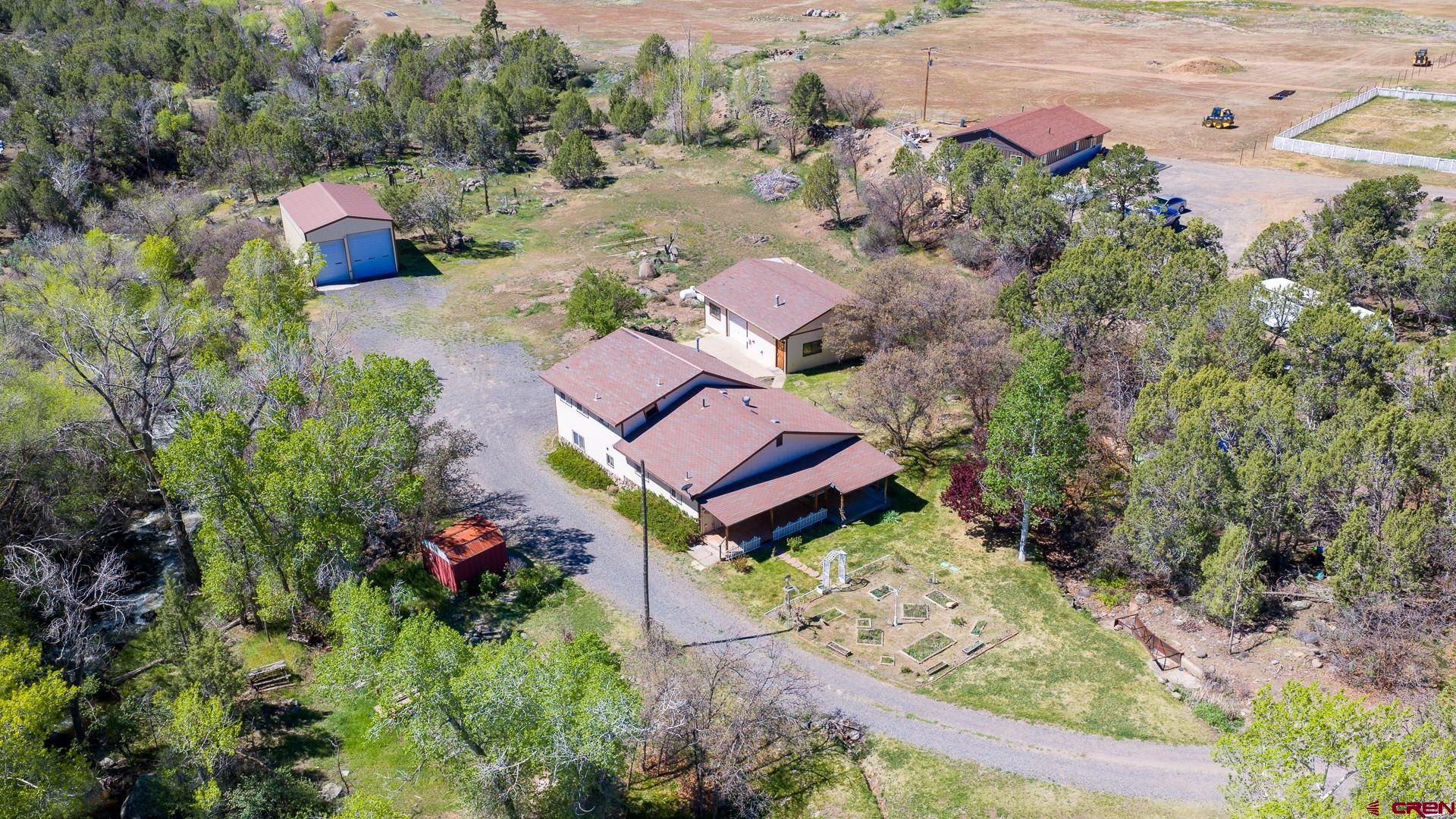 Welcome to your creekside oasis with sweeping San Juan Mountain and Grand Mesa views! Tucked down a private drive on 2.5 acres, this 3 bedroom, 3 bath home offers over 2,000 sq. ft. of comfortable living space surrounded by a diverse canopy of trees and more than 800 feet of creek frontage. This hard to find setting is accompanied by a detached 36x26 finished garage/shop complete with a half bath, utility sink, plumbed air, 220 electric, and forced-air heat. You’ll also find a 24x40 pole barn-style building with concrete floor, power, and two oversized garage doors measuring approximately 9'x12' and 12'x13'  ideal for RVs, boats, campers, equipment, or extra storage. Inside, the spacious primary suite features beautiful views, a walk-in closet, and a 3/4 bath with double vanities. Step out onto the deck and take in the peaceful setting, expansive views, and the sound of the stream below. With several potential gathering or relaxation spots along the creek, a sprinkler system for the yard, abundant wildlife, and no HOA or covenants, this property offers the rare combination of privacy, usability, and natural beauty. Come experience your own slice of Western Colorado paradise.