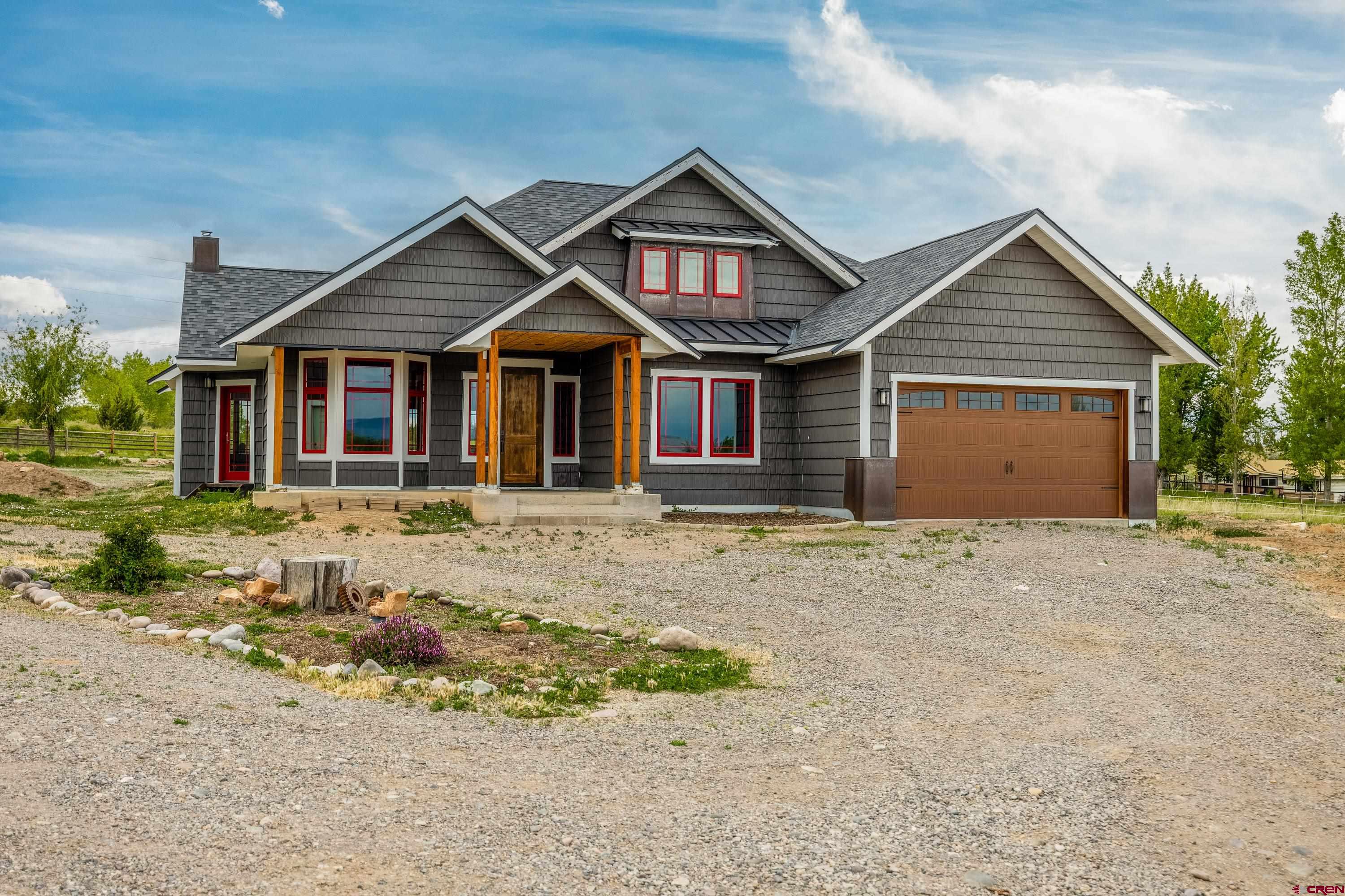 Outstanding custom home offering 1,921 sq. ft. of beautifully designed living space on 3.79 irrigated acres, complete with a 769 sq. ft. mother-in-law studio apartment, and 1400 sq.ft shop. With mountain views, seasonal ponds, and quality custom finishes throughout, this property offers the perfect blend of comfort, functionality, and the ability to bring your animals for country living.  The main residence features 3 bedrooms, 2 bathrooms, an attached garage, and an open-concept layout with high ceilings, abundant natural light, Oak hardwood floors, Alder doors/trim, and thoughtfully crafted details throughout. The spacious living room with wood burning fireplace flows seamlessly into the kitchen, creating an ideal setting for everyday living and entertaining.  The kitchen is highlighted by custom Alder cabinets, steel countertops, a large center island and west-facing windows overlooking the backyard and covered patio. Just off the main living area, a charming room with bay windows provides the perfect space for a home office, reading room, or flex space.  The primary suite offers a relaxing retreat with French doors leading outdoors, a walk-in closet, and a bathroom featuring a custom tile shower with dual showerheads. A spacious laundry/mudroom off the attached garage adds convenience and functionality.  A standout feature of the property is the detached 1,400 sq.ft shop/garage and attached studio apartment. The garage is built with 6in (4500 psi) concrete flooring, in-floor heat, 220V power, and two 10x12 overhead doors—ideal for vehicle projects, hobbies, storage, or recreational equipment. Adjacent to the shop, the 769 sq. ft. studio apartment includes high ceilings, a bathroom, laundry area, and generous storage space, offering excellent potential for multi-generational living, guests, or rental income.   The irrigated acreage includes two seasonal ponds for your enjoyment and allows for the perfect setup for your animals. Positioned above neighboring properties, the home enjoys views of the surrounding mountains and countryside.  This unique property offers exceptional versatility, privacy, and room to make it your own.