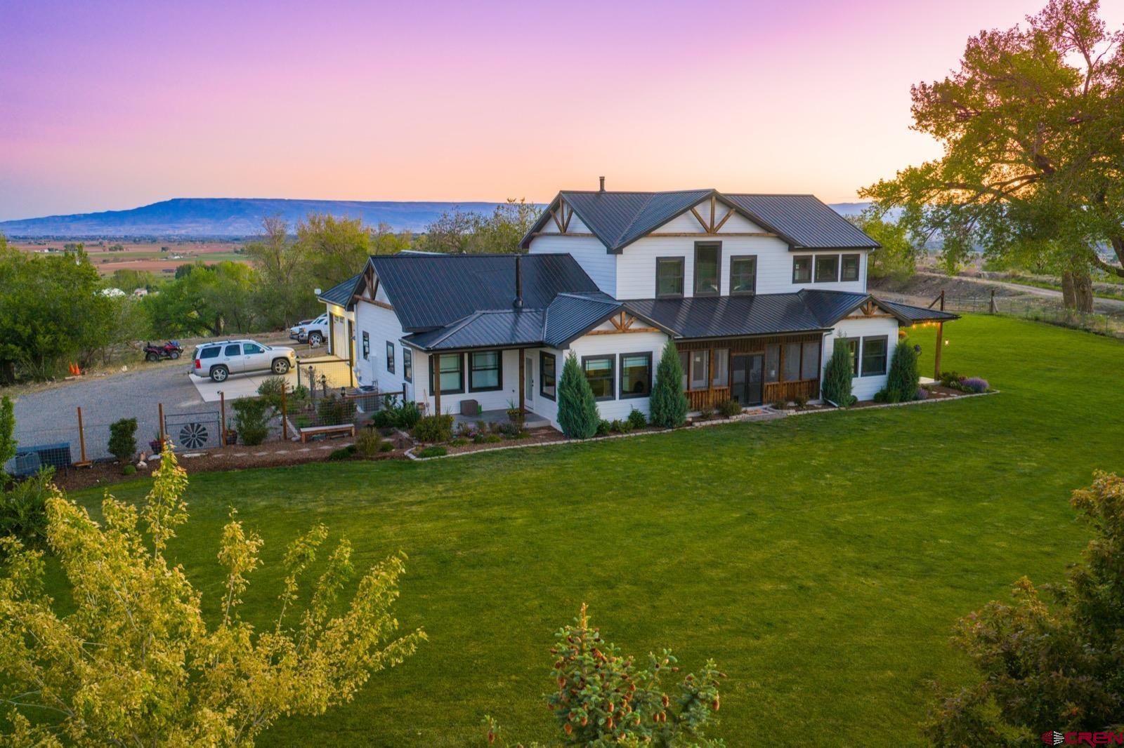 Skybreak Mesa Ranch offers the kind of acreage buyers look for in the Montrose area: usable irrigated ground, meaningful improvements, unparalleled privacy, spectacular views in every direction, and wide-ranging topographic character to create a ranch that feels both functional and distinctly its own.  Key Features: •Residence: The 2-story modern farm-house style residence with a wrap-around covered porch is substantial with 3,474± total square feet. Included is a 1,000± square foot accessory dwelling unit (ADU) providing living space flexibility as well as a full unfinished basement.   •Additional Improvements: A newly built and insulated 64’x40’ shop; a horse set up with a tack room, 64’x12’x12’ lean-to shelter, a second free-standing horse shelter, an electric-fenced and irrigated pasture, and a hay storage shelter; a fully-fenced vegetable garden with raised beds and fruit trees attached to a drip irrigation system, greenhouse, frost free spigot, and electric power; a fully fenced, expansive, and level to gently sloping yard connected to a pressurized sprinkler system; mature landscaping connected to a drip irrigation system; an RV pad with a 50 Amp electrical hookup, water and septic connections;  and 2 chicken coops with water and electric. •Acreage: 85± deeded and perimeter-fenced acres with a mix of irrigated land, flat usable ground while also featuring mesa topography, slopes, draws, tree cover, dense forest, and an elevated setting that creates unparalleled privacy and breathtaking views. The home sits on top of the mesa above the surrounding valleys. This setting provides 360-degree views from the home that include the Grand Mesa to the North, Black Canyon National Park and the Town of Montrose to the East, Cimmaron Mountain and the snow-capped, 14,000-foot San Juan Mountain Range to the South, and the Uncompahgre Plateau to the West. Built in 2020 by the current owners, the main home offers 3 large bedrooms, an office, 3 bathrooms, a dining room, open concept kitchen and living room, and a loft. The ADU includes 1 bedroom, 1 bathroom, a full kitchen, a living area, and a sunroom. The 3-car garage is extra deep providing additional room for storage or your toys.  Connected to the main house through the laundry access area, the ADU can function as part of the main home or as a more independent living space for guests, extended family, or on-site support. Separate furnaces, water heaters, and A/C systems service the main residence and the ADU. The residence also has a full, unfinished basement with 9’ ceilings to provide a large storage area and future potential living or entertaining space, including two separate areas with windows that could be finished into spacious legal bedrooms. From the basement there is also access to two fully sealed, large crawl spaces for extra storage. A covered porch surrounds the main home where you can relax and enjoy the impressive mountain views and peaceful surroundings. In addition, there is a large, south-facing, screened-in porch accessed by both the main home and ADU.  Water is another valuable asset for this ranch. The property includes 21 shares of the Uncompahgre Valley Water Users Association (UVWUA), with irrigation water currently supporting the two hayfields through a system of irrigation ditches connected to the main irrigation canal, and gated pipes. The horse pasture and lawn are also watered with the UVWUA irrigation water through a pressurized sprinkler delivery system. In addition, the property includes deeded water rights to a portion of the flow from year-round springs on the far west side of the property. City water is connected to the residence where it is treated by a whole house filtration system before it enters the home’s plumbing. Five frost free spigots also provide city water to other areas of the property.