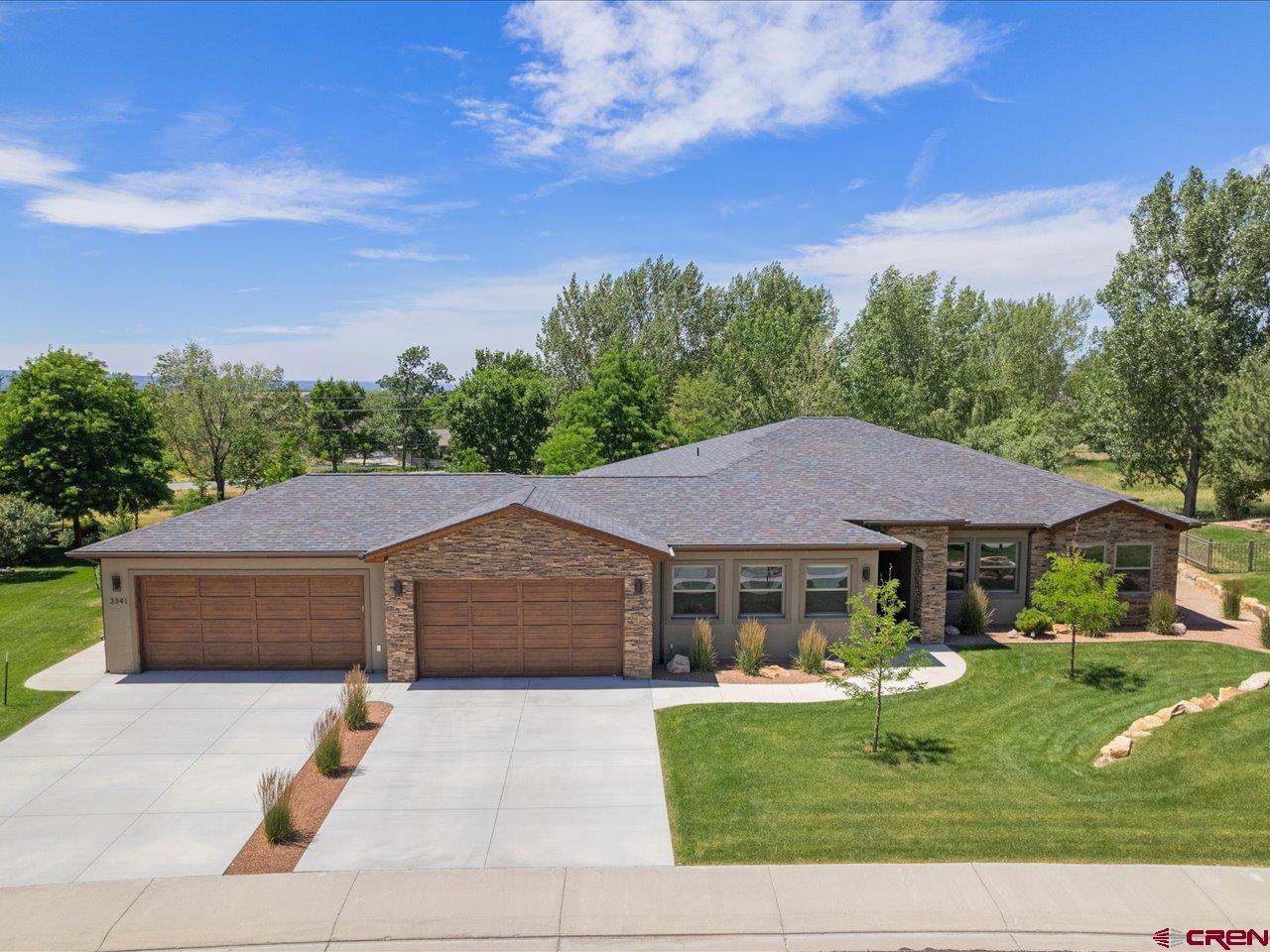 Welcome to this exceptional ranch-style home custom-built by local luxury builder Greg Comstock offering the perfect blend of luxury, comfort and lifestyle - located in the highly desirable Brown Ranch subdivision of Montrose. Featuring 2,601 square feet of thoughtfully designed living space, this single-level residence features 3 bedrooms, each with an ensuite bathroom + ½ bath for guests, a dedicated office, and an impressive 1,314-square-foot four-car garage with workshop space. Designed with both comfort and accessibility in mind, the home was engineered with a foundation over-dig to accommodate low 2-inch thresholds and features a covered entry with a 42-inch-wide front door. Inside, you'll find beautiful Bernina Hickory-Fora hardwood flooring throughout the main living areas, solid-core 8-foot doors, insulated interior walls, and an open floor plan centered around a cozy fireplace in the great room. The chef's kitchen is appointed with custom alder cabinetry, 42-inch upper cabinets, under-cabinet lighting, pull-out shelving, nine pot drawers, and an oversized granite island with seating for six. Premium KitchenAid appliances include a 36-inch cooktop, convection oven/microwave combination, dishwasher, and side-by-side refrigerator. The home also includes the washer, dryer, and four wall-mounted televisions. The spacious primary suite and guest accommodations are complemented by beautifully finished bathrooms featuring floor-to-ceiling tile surrounds, tiled floors, and granite countertops. The primary suite walk-in closet includes custom built wardrobe cabinets enriched with deep drawers to keep your closet looking organized.  A dedicated office with built-in desk provides an ideal workspace. Additional conveniences include a large laundry room with upper and lower cabinetry, utility sink, and generous storage. Outdoor living is equally impressive with a large covered patio featuring cedar wood ceiling, ceiling fans, and sweeping views west toward the Uncompahgre National Forest. A 20-foot-wide HOA easement along the south side of the property enhances privacy and openness. The oversized four-car garage is a standout feature, offering 16-foot and 18-foot-wide garage doors, epoxy/polyurethane finished floors, a Mitsubishi mini-split heating and cooling system, and an enclosed maintenance room housing the home's mechanical systems, on-demand water heater, and crawl space access. Additional upgrades include central air conditioning, a Water Drop reverse osmosis system, heat tape in the north and east gutters, extensive drainage systems directing water away from the home, city water for landscape drip irrigation, and HOA-provided irrigation water for the lawn and trees. Set on a beautifully landscaped lot with approximately 8,300 square feet of lawn area, this meticulously maintained property combines quality craftsmanship, energy-efficient features, outstanding storage, and breathtaking Colorado views in one remarkable package.