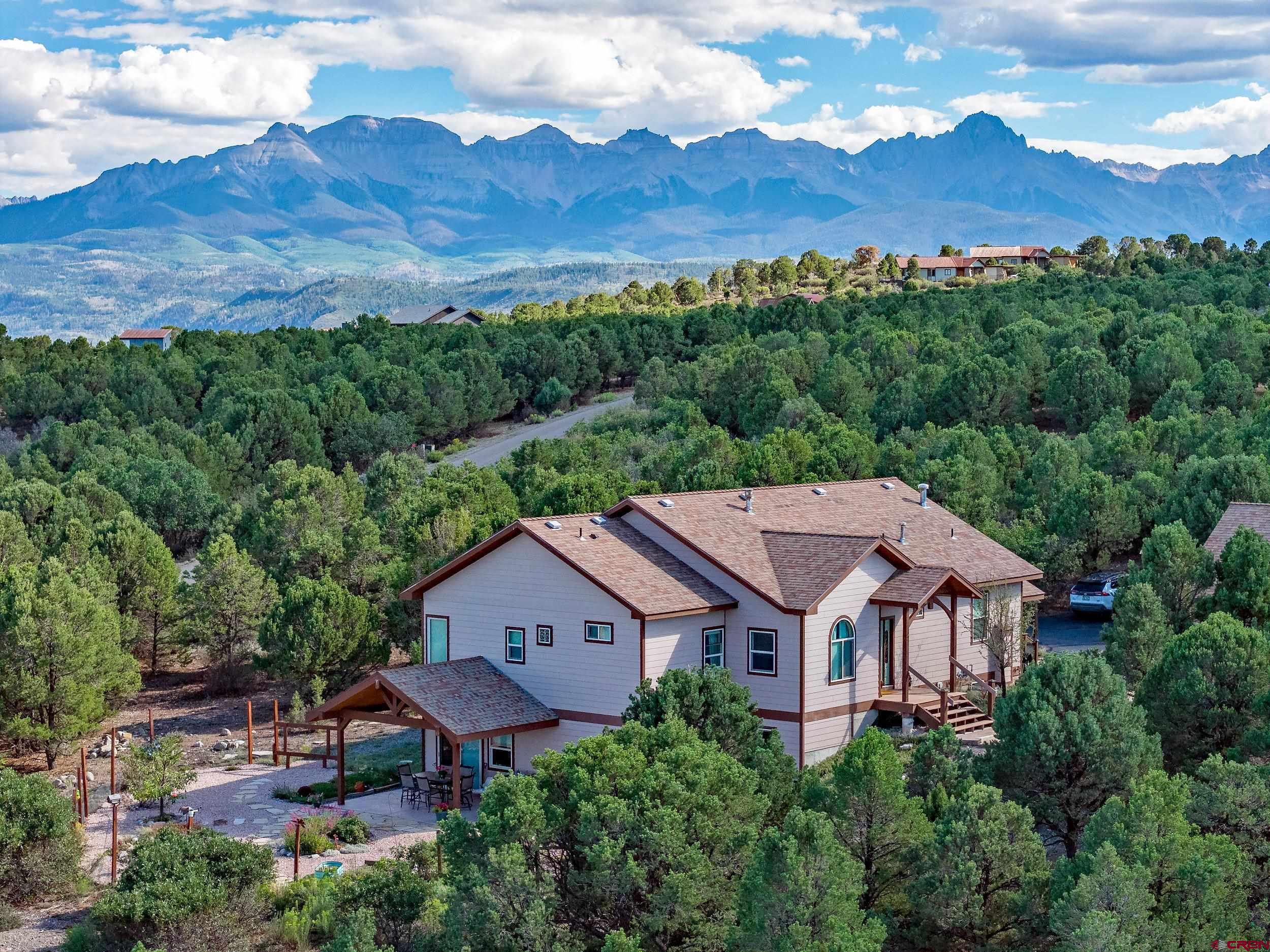 Check out the other listings in Ouray county at this price point with this square footage, 3 bedrooms, 3 bathrooms, 3+ car garage, with this amount of acreage, prior to viewing this one - you'll quickly discover why!  This custom built home sits on 2.89 acres with amazing views of the Cimmarons from the main floor.  Access to the property is totally on paved roads along with an asphalt driveway.  The exterior of the home has a large fenced in area on the north side with beautiful flowers and gardening areas.  Inside the fenced-in area is a great covered patio which will keep you out of the intense sun and allow you to grill without getting wet if it's raining/snowing.  There is also a large deck on the east and south side of the house to take in those amazing Cimmaron views - especially at sunset. The exterior of the home has fiber cement siding for low maintenance and fire protection.  Finally, for the exterior is the 816 sq. ft. detached garage which is setup for 3 car spaces and a work area.  The wall in the work area could easily be removed to make it a 4 car garage!  There is also a 2nd story on the garage with a separate entrance which allows for tons of storage or whatever you can think of.  Moving to the interior of the home - There is a true chef's kitchen with a prep island and sink.  There are also numerous cabinets, quartz counters, newer top of the line stainless steel appliances including a built-in warming drawer, two refrigerators, Bosch dishwasher, Fisher & Paykel wall oven, Fisher & Paykel five burner gas cooktop, and new faucets. Just off the kitchen is a separate formal dining area with those amazing views and direct access to the deck and living room.  The living room has 12 foot ceilings, a floor to ceiling stone fireplace, and the views.  The main floor also has the primary bedroom with 10 ft. coffered ceilings, a 5-piece bath, jetted tub, sweeping views, and dual walk-in closets.  Finally on the main floor is a large office/study area and a full bath just across the hall.  The lower level of the home has a large family room with a wet bar, fridge, and microwave, game table area, and a large screen TV area with a media closet behind it.  You will also find a private guest suite with it's own 3/4 bath.  There is also one additional bedroom on the lower level.  Finally, there is a large space currently used as a fitness room and hot tub area as well as a wine cellar/closet.  Some other notable items about this property:  whole home water filter system, fiber optic internet, main floor gas forced air heat with humidifier and electronic air cleaner, lower level in-floor radiant heat, high-end low maintenance laminate flooring, and a gas fireplace on each level.  The owners had the septic pumped in Sept 2025 and everything was functioning properly.  Radon was tested Aug. 2025 and came in at 2.4.  broker can provide receipt and results if requested.  Utility bills for past year posted in MLS docs.  NOTE: some furnishings are available for purchase - contact broker for details.  There is a 3D virtual tour for this property - if you are viewing this listing on a website that does not provide it, contact broker directly and he will email you a link.