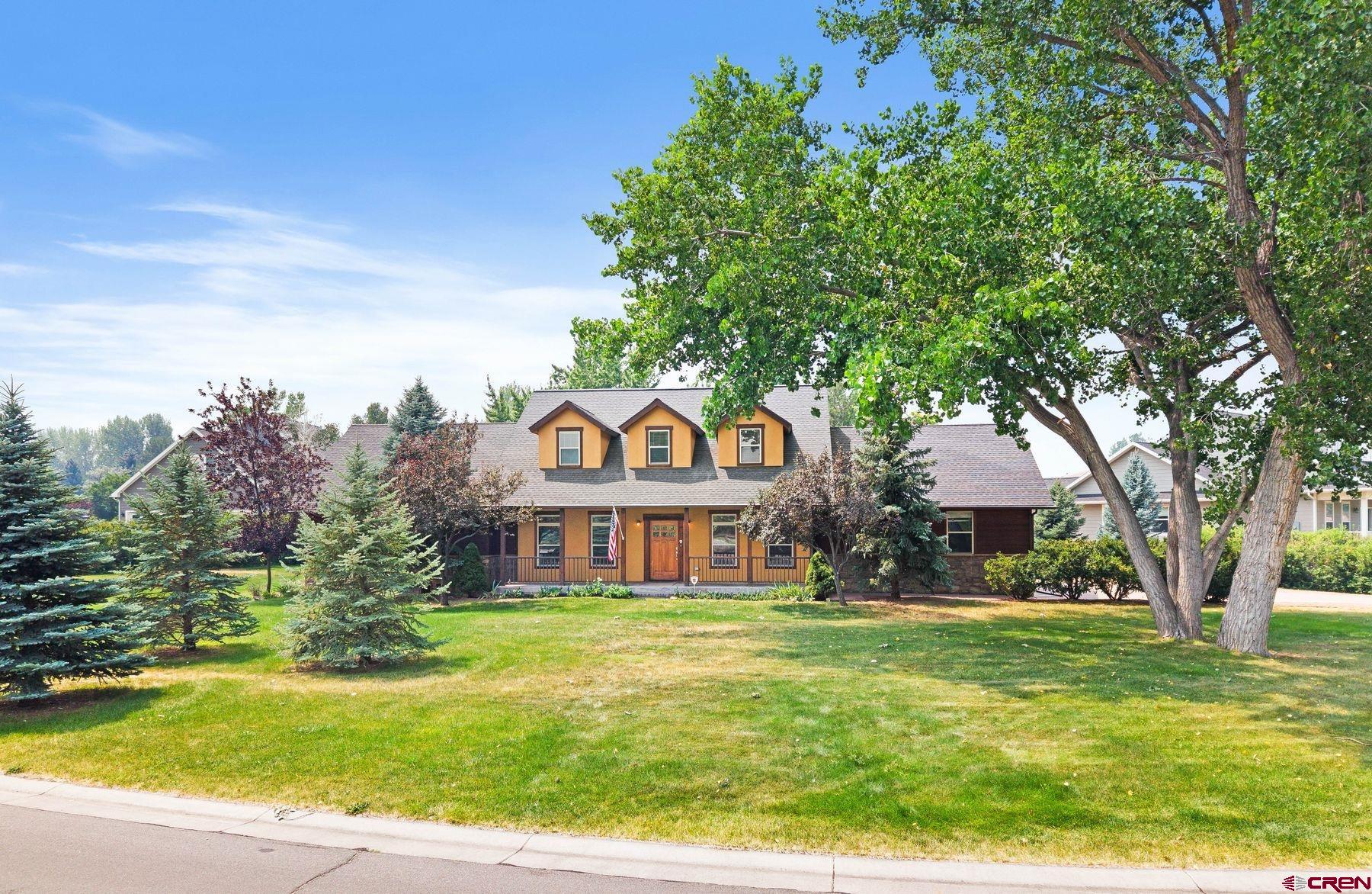 A rare opportunity to own a timeless Craftsman-style home in one of Montrose's most sought-after neighborhoods. Nestled on a meticulously maintained .62-acre lot, this exceptional property offers the perfect blend of elegance, privacy, and convenience. Towering mature trees, lush landscaping, and a truly park-like setting create a peaceful retreat where every season can be enjoyed from the comfort of your own backyard. Offering 3,048 square feet of thoughtfully designed living space, the home showcases warm hardwood flooring, a striking stone fireplace, spacious gathering areas, and an abundance of natural light throughout. The beautifully appointed kitchen is designed for both everyday living and effortless entertaining. The main-level primary suite provides the ease of single-level living and features a spa-inspired bath with generous closet space. Upstairs, the versatile bonus room offers endless possibilities as a home office, media room, fitness studio, or additional living space. Adjacent to the bonus room, a spacious guest suite with vaulted ceilings and a well appointed private en-suite creates the perfect retreat for family or overnight guests. Step outside to experience one of the property's most exceptional features—a serene backyard oasis designed for relaxing, entertaining, or simply enjoying the quiet beauty of nature. Fully irrigated grounds, mature shade trees, and lush landscaping provide remarkable privacy, creating a setting that feels more like a private park than a residential backyard. Located in an established neighborhood renowned for its beautiful custom homes, residents enjoy access to a picturesque neighborhood lake complete with walking trails, creating a lifestyle centered around recreation, nature, and community. Just minutes from shopping, dining, golf, hiking, and the endless outdoor adventures that make Western Colorado so desirable, this home offers the perfect balance of peaceful living and modern convenience. This is more than a home—it's an exceptional lifestyle in one of Montrose's premier neighborhoods. Furnished photos staged virtually.