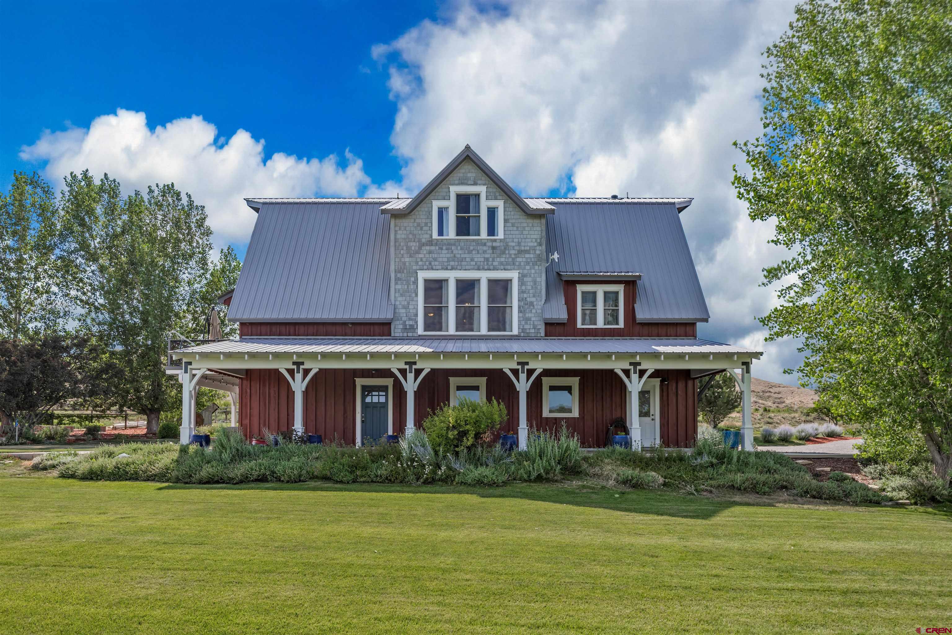 Some homes simply provide a place to live. Others invite you into an entirely different way of life.    Inspired by the simple beauty of a century-old farmhouse and built with the efficiency and comfort of a modern home, this architecturally striking barn-style residence is truly one of Montrose County’s most distinctive properties. Set on more than 3 irrigated acres with no HOA, the property offers sweeping views of the surrounding valley and mountains, colorful Western Colorado sunsets, and brilliantly clear night skies.    Inside, specialty woods and handcrafted details give the home warmth and authenticity rarely found in newer construction. The main living level features an open great room, spacious dining area, walk-in pantry, and beautifully remodeled kitchen with gorgeous cabinetry and vertical-grain fir flooring. The private primary suite is also located on this level and includes an expanded walk-in closet and an updated bath with a step-in shower and Victorian-style soaking tub.    The upper level offers two generously sized bedrooms, a full bath, laundry room, additional storage, and a charming sitting or flex area that could serve as an office, reading retreat, playroom, or creative space.    The lower level may be one of the property’s greatest surprises. A heated and cooled shop with 110- and 220-volt power, an updated half bath, and direct access to the oversized four-car garage provides exceptional flexibility for vehicles, woodworking, hobbies, equipment, a home-based business, or future finished living space.    Outside, the property is equally impressive. irrigated grass pastures, a sprinkler system, garden boxes, mature landscaping, fruit trees, a garden shed, wood shed, improved driveway, multiple gated areas, covered porches, an upper deck, and a patio create an inviting setting for animals, gardening, recreation, and peaceful country living. Recent improvements include a remodeled kitchen and dining area, updated bathrooms, an expanded primary closet, mini-split heating and cooling in the shop, improved garage floors and doors, exterior staining, metal roofing over portions of the home and patio, upgraded septic access, fiber internet, RV plug conduit, and numerous property and landscaping enhancements.    Whether envisioned as a hobby-farm, workshop property, garden sanctuary, or simply a remarkable country home close to town, this one-of-a-kind property offers the space, character, and freedom to create a lifestyle all your own.
