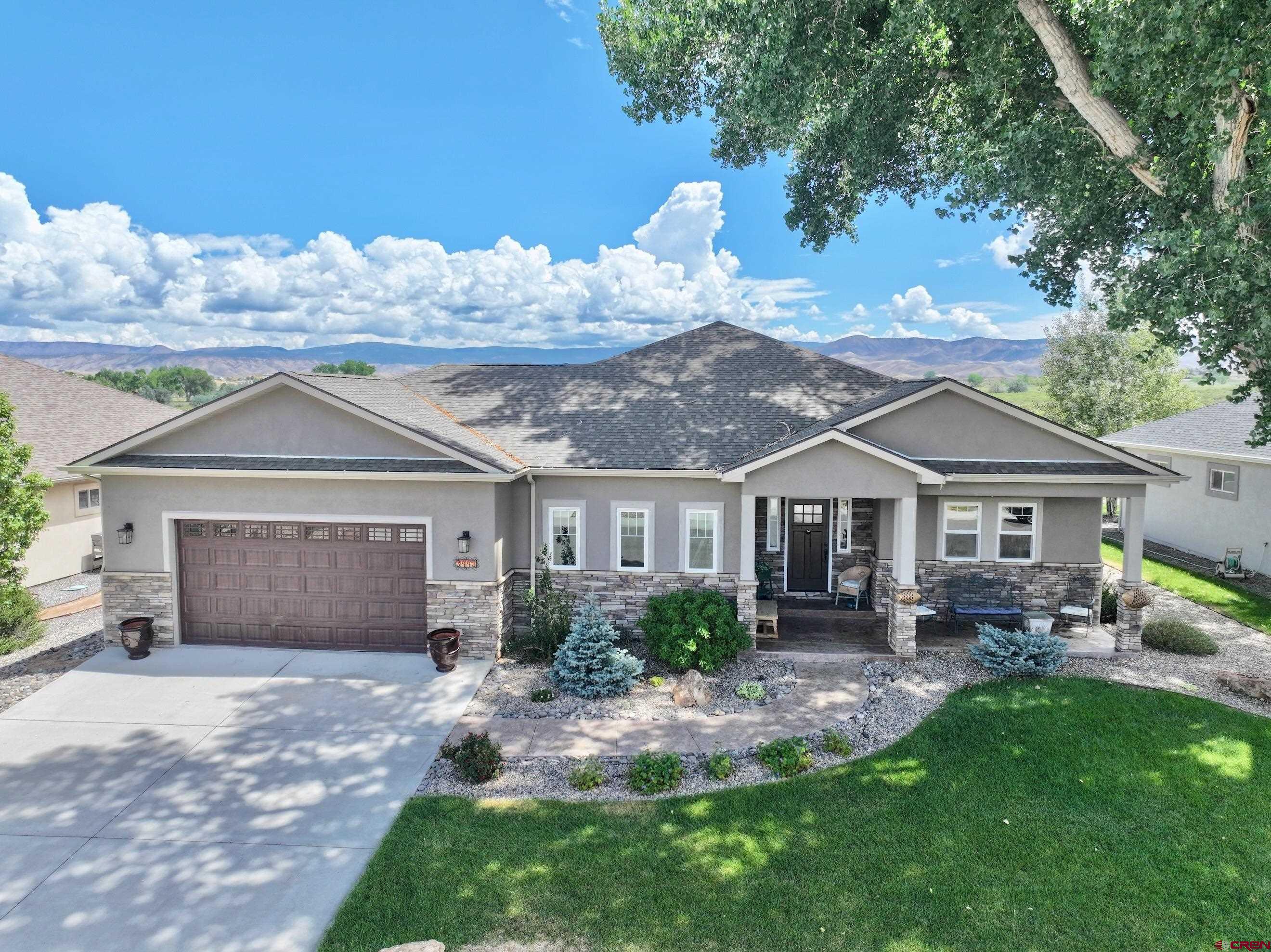 Experience luxury Colorado living in this exceptional custom home in desirable Brown Ranch, where breathtaking open space, Storm King, and Uncompahgre views create an unforgettable setting. A welcoming covered front porch, framed by a majestic cottonwood tree, vibrant hollyhocks, and mature landscaping, sets the tone for this beautifully appointed home.  Inside, expansive windows fill the open floor plan with natural light, while a dedicated office offers the perfect work-from-home space. The gourmet kitchen features quartz countertops, abundant cabinetry, a large island, and seamless flow into the spacious living and dining areas.  The private primary suite is a true retreat with a spa-inspired bath featuring dual quartz vanities, a stone walk-in shower, soaking tub, and an oversized walk-in closet with direct access to the laundry room. An oversized three-car tandem garage with a workshop area provides exceptional storage and versatility. Complete with covered front and back porches, this thoughtfully designed home offers the perfect blend of luxury, comfort, and stunning views in one of Brown Ranch's most desirable locations.