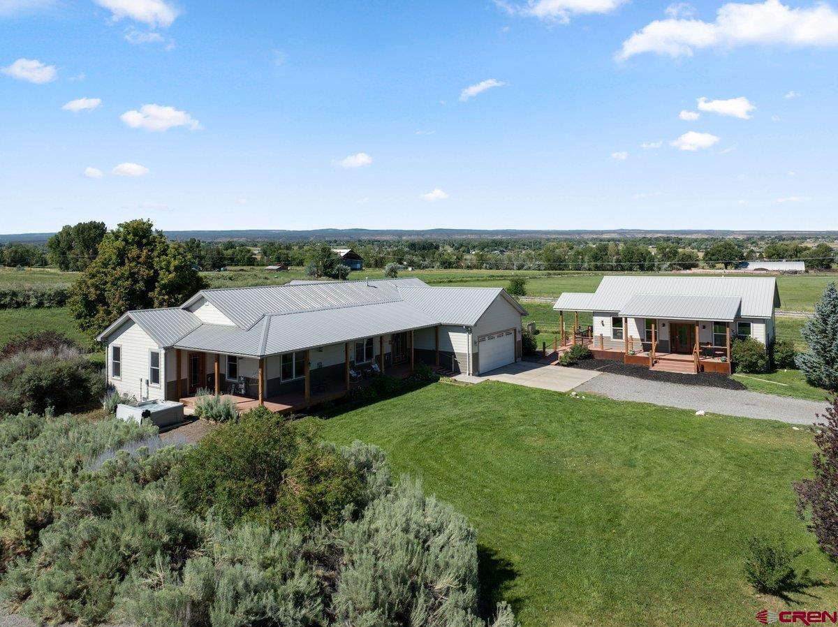 WHERE COUNTRY LIVING MEETS COLORADO LIFESTYLE  A Private Spring Creek Retreat • 12.59 Irrigated Acres • Guest Home • Mountain Views  Imagine mornings on the wrap-around porch, evenings gathered around the fire, and quiet afternoons overlooking irrigated alfalfa fields stretching toward the southern mountains. Here, the pace slows down—and the possibilities expand.  Set in the sought-after Spring Creek area just 15 minutes from Montrose, this remarkable 12.59-acre property offers a rare combination of comfortable living, productive irrigated acreage, guest accommodations, and the freedom to create your own Colorado hobby farm.  At the heart of the property is a charming 2,215-square-foot farmhouse offering three bedrooms, two baths, and an inviting open-concept design. The living room, dining area, and kitchen come together in a spacious gathering place filled with warmth and natural light. The kitchen offers a generous bar for casual dining, a dedicated dining area, and a separate pantry with a built-in coffee bar. A gas fireplace adds warmth and ambiance to the living room, while geothermal heating and cooling provide efficient year-round comfort, and Solar with the main house.  The outdoor spaces are equally inviting. A welcoming wrap-around front porch and covered back patio provide multiple places to relax, entertain, or simply take in the views. Mature shade trees, landscaped grounds, garden containers, and a hot tub create a private outdoor oasis overlooking the irrigated alfalfa pastures and mountain landscape.  Then there is the 1,083-square-foot guest home, built in 2016, offering two bedrooms, one bath, central heat and air, and a ProPanel roof. Whether used for guests, multigenerational living, a private retreat, or a long-term rental, it adds tremendous flexibility and value. This guest home is being sold completely FURNISHED.