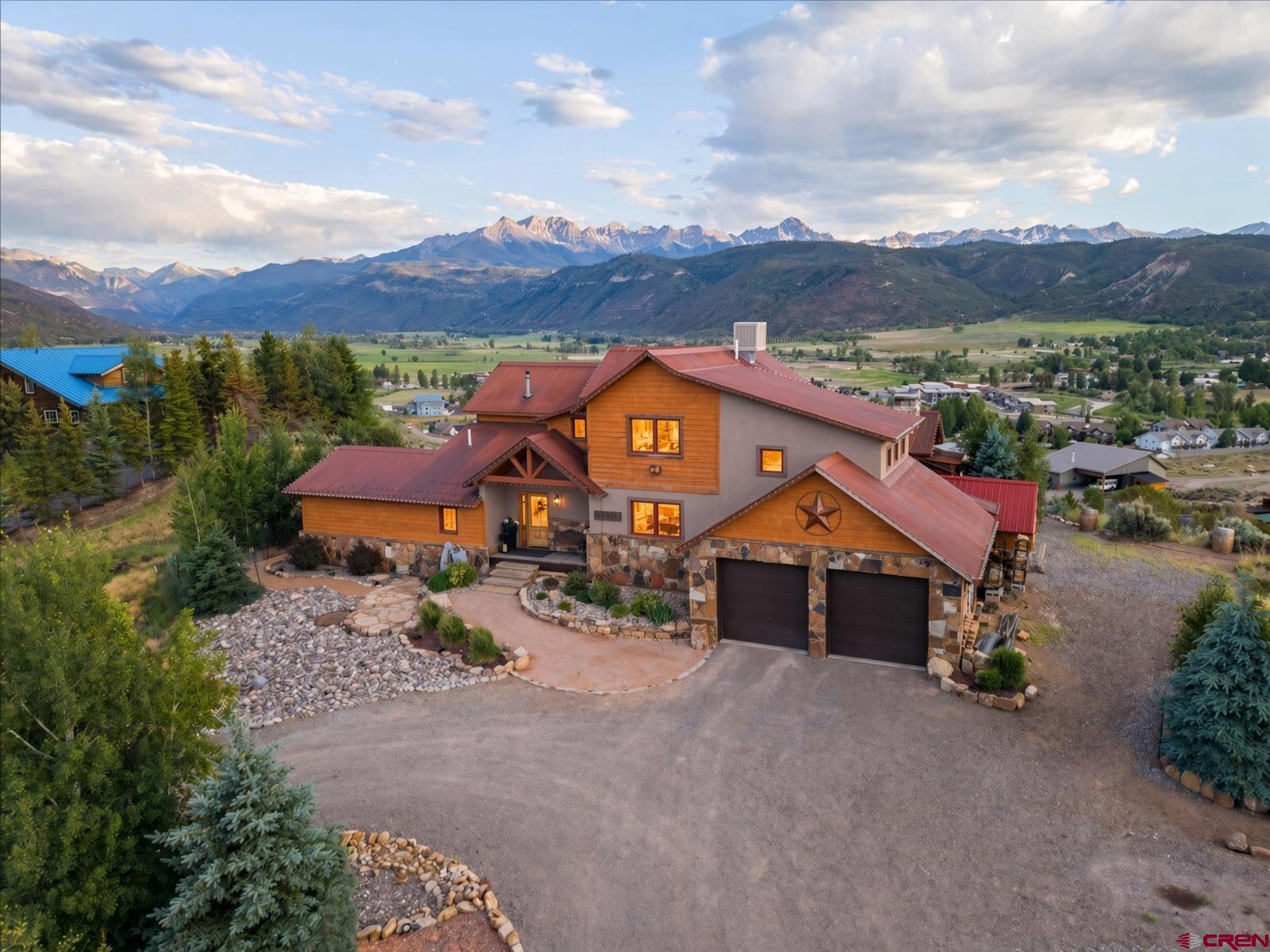 This rare, one-of-a-kind mountain estate commands a premier position on the edge of Ridgway’s prestigious Vista Terrace subdivision, high above town on a quiet cul-de-sac. Enveloped by the majestic San Juan Mountains, the home delivers dramatic 180- to 360-degree panoramic views of snow-capped peaks and Cimarron Range that change with every season and every hour of the day. Set on 1.09 private acres with lush landscaping of Aspens, Blue Spruce, mature trees, and deer fencing, this mountain estate features a sophisticated mix of stone, stucco, wood, and rusted metal siding beneath a metal roof. The residence offers 2,900 square feet of refined living space, including a 477-square-foot basement food storage and fitness room, with 3 bedrooms and 3 baths (plus the potential for a fourth bedroom downstairs). More than 3,500 square feet of outdoor living space delivers a seamless indoor-outdoor lifestyle rarely found. In 2022 the home was thoughtfully enhanced with a custom built-in executive office designed for two, a remodeled media room, loft space, laundry room, and a finished basement section with 8-foot ceilings that includes a workout room and closet. The partial finished basement provides massive storage with metal racks, an open food storage pantry with shelving, and flexible use. That same year the outdoor living areas were transformed with the covered entertainment pavilion, stone fireplace, flagstone firepit, expanded patio, walkways and lush, professionally designed landscaping framing the mountain views. A high-efficiency pellet stove insert was installed in 2025.  Solid wood interior doors, knotty alder kitchen cabinets with pull-out drawers, granite countertops, convection oven, and professional-grade appliances complete the main living areas. The primary suite offers stunning mountain views, a perfect way to start your day... along with a jetted tub and walk-in closet. In-floor heating, an evaporative cooler, double-pane windows, and $32,000 in solar power deliver comfort and efficiency. Floors include a refined mix of wood, tile, and carpet. The finished garage includes cabinets and storage racks. Step outside into a true mountain lifestyle. The covered entertainment pavilion features a wood-burning stone fireplace, propane hook-up for your gas grill, leathered granite countertops, bar seating, under-counter lighting, and a large sliding wood door brings the mountain views in. Accent lighting, outdoor receptacles, and an outlet for a television make it ready for year-round gatherings. A flagstone firepit and thoughtfully designed patios and pathways invite evening conversations under the stars. The property offers RV parking suitable for short stays and possibly longer with guidelines, space for multiple vehicles, a covered front porch, and a fully equipped estate-quality chicken coop, an exceptional amenity for the serious hobbyist. A 7-zone drip system and thoughtful dry scape landscaping keep maintenance low while maximizing beauty. Serene yet connected, this quiet neighborhood sits minutes from the heart of Ridgway and only 15 minutes from Ouray’s hot springs, waterfalls, and historic downtown. World-class recreation surrounds you: Telluride skiing, hiking, mountain biking, 4-wheeling, rafting, paddle boarding, fishing, hunting, and camping are all within easy reach. Perfect as a primary residence, family retreat, or second home with the added appeal of original home ownership. Wake up to breathtaking mountain peaks each morning and gather under starlit skies each evening. This is Colorado mountain living at its finest, schedule your private showing today.