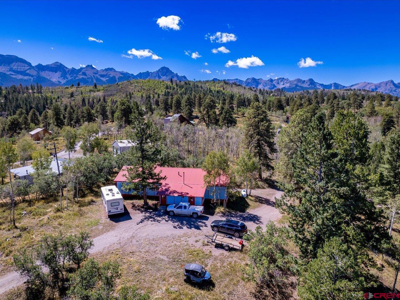 Open, Spacious, Light & Bright with Mountain Views! Enjoy comfortable mountain living in this spacious 4-bedroom, 3-bath home featuring an open floor plan designed for everyday living and entertaining. The open kitchen offers stainless steel appliances, a breakfast bar and an abundance of cabinetry, while the formal dining room and cozy living room provide plenty of space to gather. A main-floor primary suite adds convenience, and the office/den with pellet stove creates a warm and inviting space for working from home or relaxing. Recent updates include newer carpet, laminate flooring and interior paint. Modern conveniences include high-speed internet, while energy-efficient double-pane vinyl windows and a durable metal roof add to the home's appeal. Step outside onto the large private deck and take in expansive mountain views, big blue skies and brilliant star-filled nights. Additional features include a lofted utility shed and an 11' x 17' heated indoor shop area with 220V service—ideal for hobbies, projects or additional workspace. With four bedrooms and multiple living areas, the flexible floor plan is well suited for a large or extended household, home office needs or potential roommate arrangements. Nestled among the trees with views as far as the eye can see, this property offers a peaceful mountain setting just minutes from National Forest lands with convenient access to Ridgway and Telluride. Come experience the space, scenery and Western Colorado lifestyle!