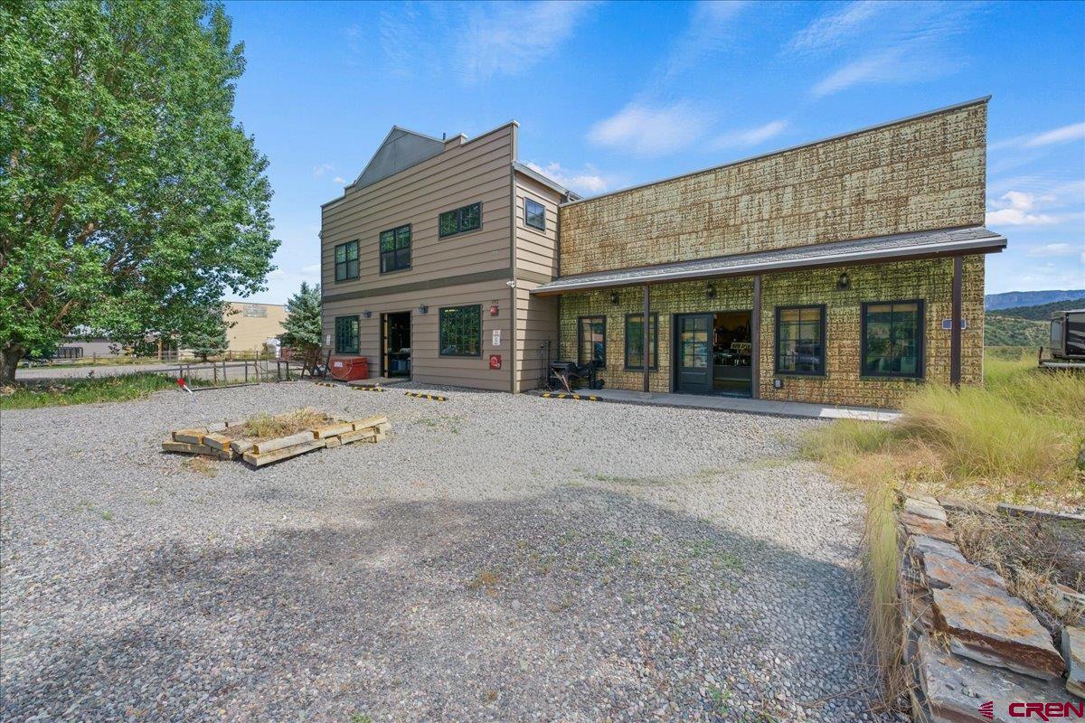 This F2-zoned mixed-use building with residence just off Highway 550in Ridgway is a smart setup for an owner-operator or investor. You can live upstairs and rent out the two ground-floor commercial units to easily offset your mortgage. The property stands out with impressive metal work inside and out. The exterior features durable metal siding designed for the mountain elements, while the interior commercial space is framed by heavy-duty steel beam construction anchored to an over-thickened concrete slab. The upper level features a spacious 1,404-square-foot, 3-bedroom, 1-bathroom apartment. Incredible views of Mt. Sneffels and the Cimarron Range. Downstairs, the fire safety infrastructure is top tier. It utilizes a freeze-proof dry sprinkler system fed by a 4-inch pipe and thrust block, guaranteeing instant water delivery with zero winter freezing risks. Complete with 14 dedicated parking spots, this property is a highly capable and turnkey setup ready for its next owner.