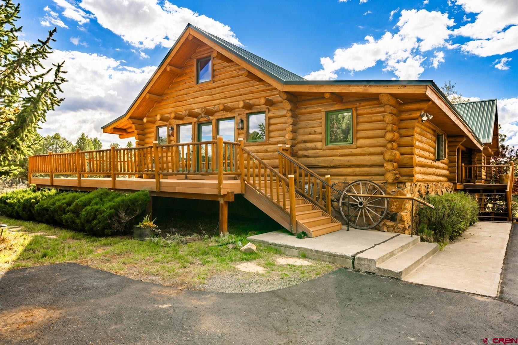 Set amongst the beautiful ponderosa, piñon, and juniper trees in the exclusive Log Hill community, this hand-hewn log home and log guest house rests quietly on 4.81 acres in Fairway Pines Estates. The San Juan and Cimarron ranges and Mount Sneffels fill the southern skyline...the kind of view that makes you pause, gratefully, in the doorway. Step inside, and this home feels like a true mountain lodge: warm, timeworn, hand-hewn logs with scored faces and tight chinking, generously scaled rooms, and mountain light pouring softly through the trees. Tucked past the trees, the house reveals itself only as you arrive. The main log home is 4,856 square feet of places to gather, linger, and stay. The finished basement and garage sit below, ready for gear and cars. A handsome two-sided wood-burning fireplace warmly ties the living room to the primary bedroom...open to the living room, yet private on the bedroom side. Yet another fireplace truly anchors the basement game room and media room for all your entertaining needs. The owners have lovingly made this home the heart of their holidays, lingering summer barbecues, and quiet winter nights...rooms that hold easy conversation and unhurried laughter. The primary suite looks out toward the magnificent mountain views...a quiet place to awaken to the gorgeous southern skyline. Extra bedrooms have warmly welcomed family and friends to stay the night, share breakfast, and settle in as if they never left. Premier golf and an exquisite clubhouse, with winding community trails, await your adventures just around the corner. This is Fairway Pines living at its most inviting: the trees close at hand, the course nearby, and the high country beautifully within reach. Ridgway and Ouray are only minutes away. The town of Telluride is a beautiful, fun forty-five-minute drive away. The guest house is tucked gently beside the main lodge is its own welcoming two-story log guest house, built in 2000 with    2,048 sunlit square feet of quiet comfort. This additional space includes two cozy bedrooms, one bath, a convenient kitchenette, a generously scaled living and dining room, a loft, abundant storage, an attached garage, and a warm wood-burning fireplace of its own. Together the homes offer six bedrooms and six bathrooms, five baths in the main house and one in the guest house. Start the day with morning coffee on the wraparound deck of this beautiful additional space. Inside, the living and dining room gathers everyone comfortably around one generous table. Upstairs, the loft offers ample, flexible space for a quiet office, a cozy media room, or a lively game room whenever you need a little more room to spread out. Storage is easy to find throughout. An attached garage keeps all your extra vehicles, toys, and mountain gear safely out of the weather. As extra living quarters or a quietly private wing when the main house is full, this inviting guest house welcomes company in without ever crowding the lodge next door.