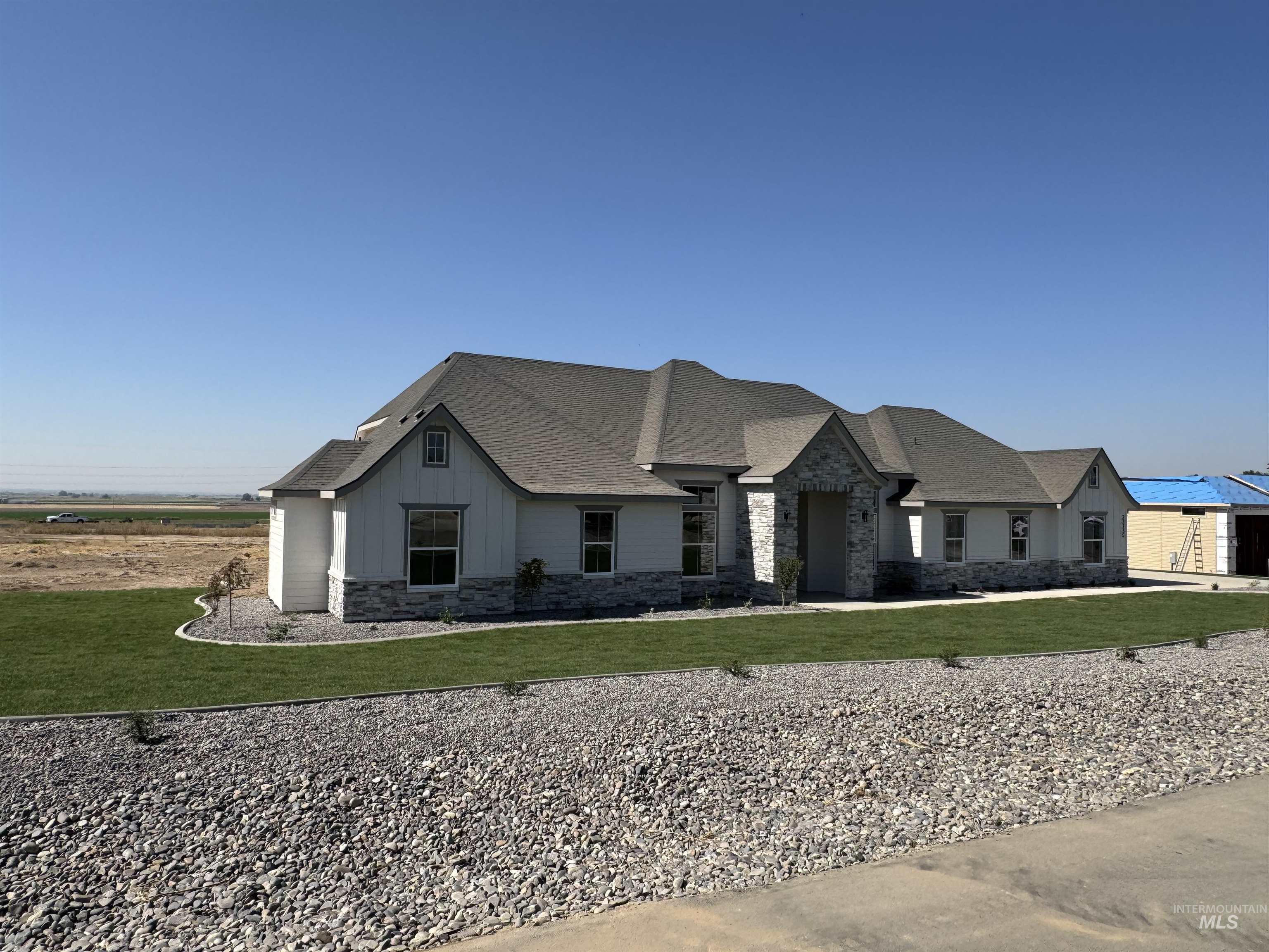 View of front of property with stone siding, a front yard, board and batten siding, and roof with shingles