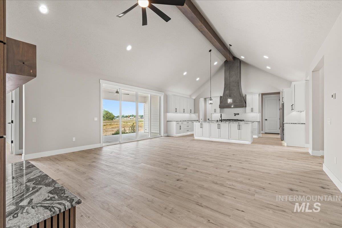 Unfurnished living room featuring beamed ceiling, light wood-style flooring, high vaulted ceiling, ceiling fan, and recessed lighting