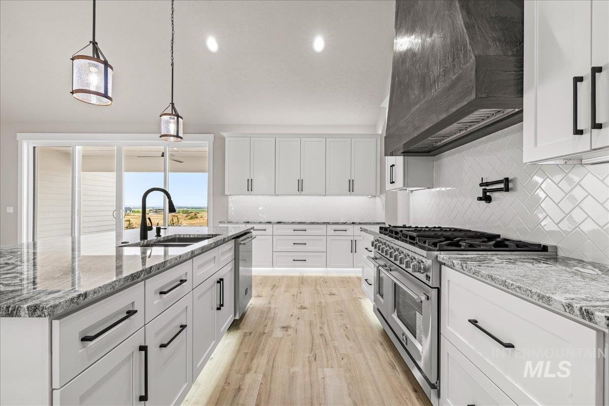 Kitchen with white cabinetry, appliances with stainless steel finishes, pendant lighting, custom exhaust hood, and recessed lighting