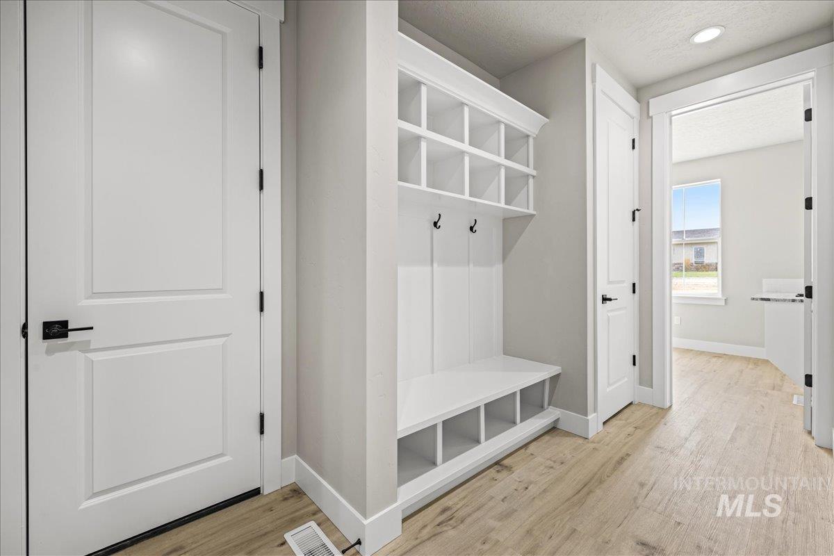 Mudroom with light wood finished floors, a textured ceiling, and recessed lighting
