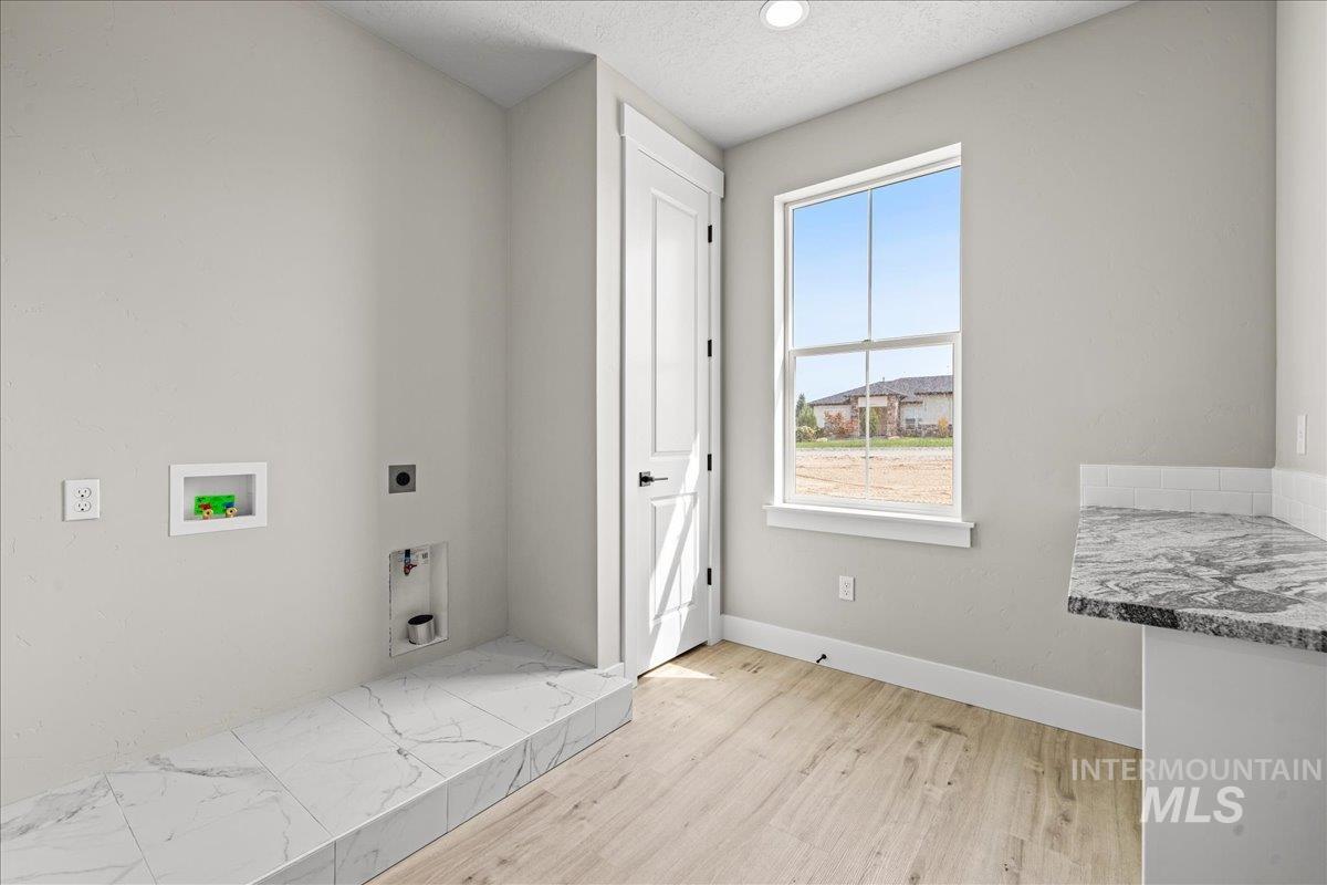 Laundry room with light wood-style floors, hookup for a washing machine, a textured ceiling, hookup for an electric dryer, and recessed lighting