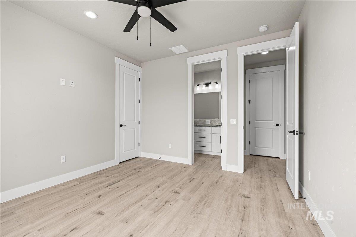 Unfurnished bedroom with connected bathroom, light wood-style flooring, recessed lighting, and ceiling fan