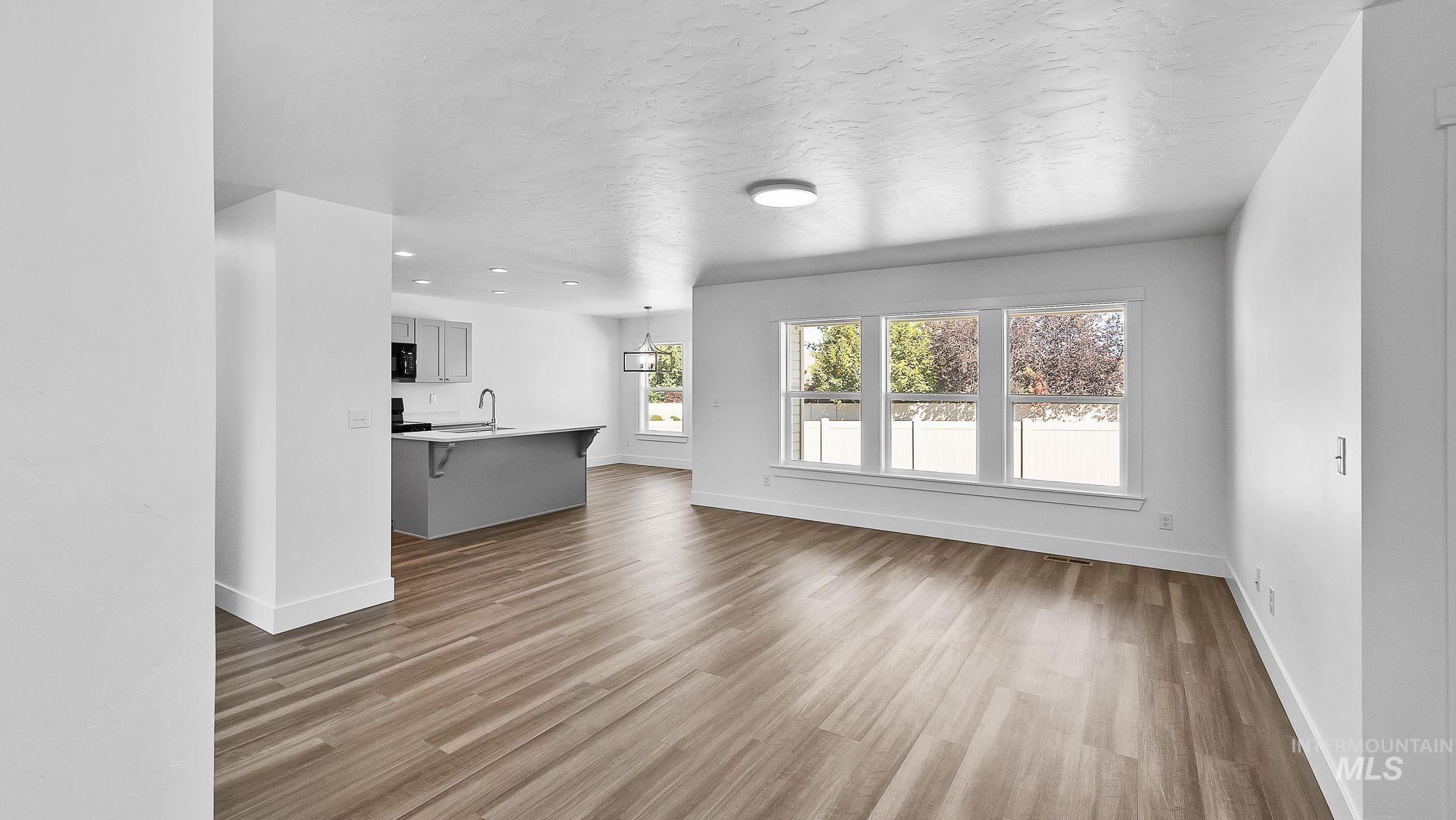 Unfurnished living room with light wood-type flooring and a textured ceiling