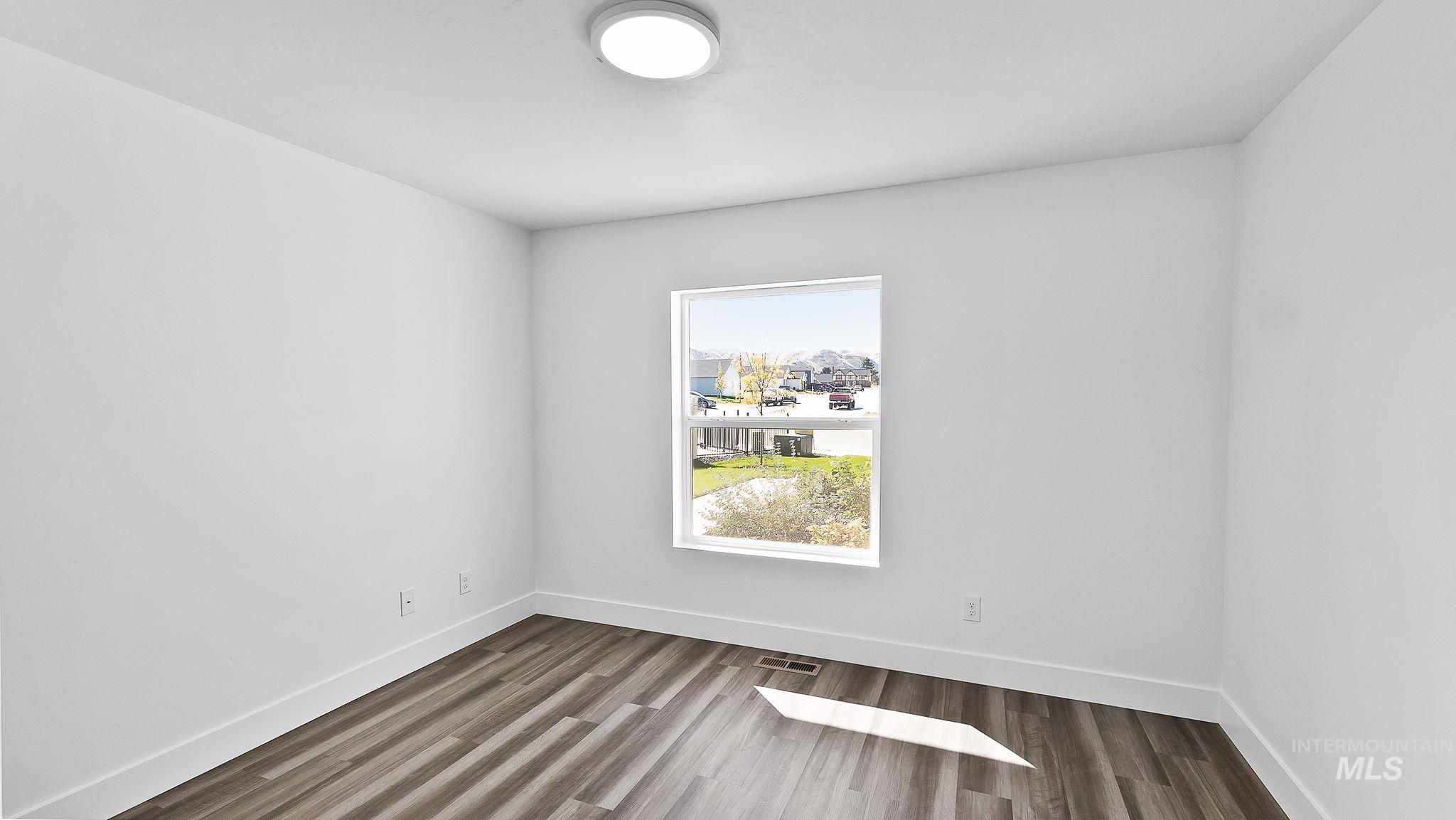 Unfurnished room featuring baseboards and dark wood finished floors
