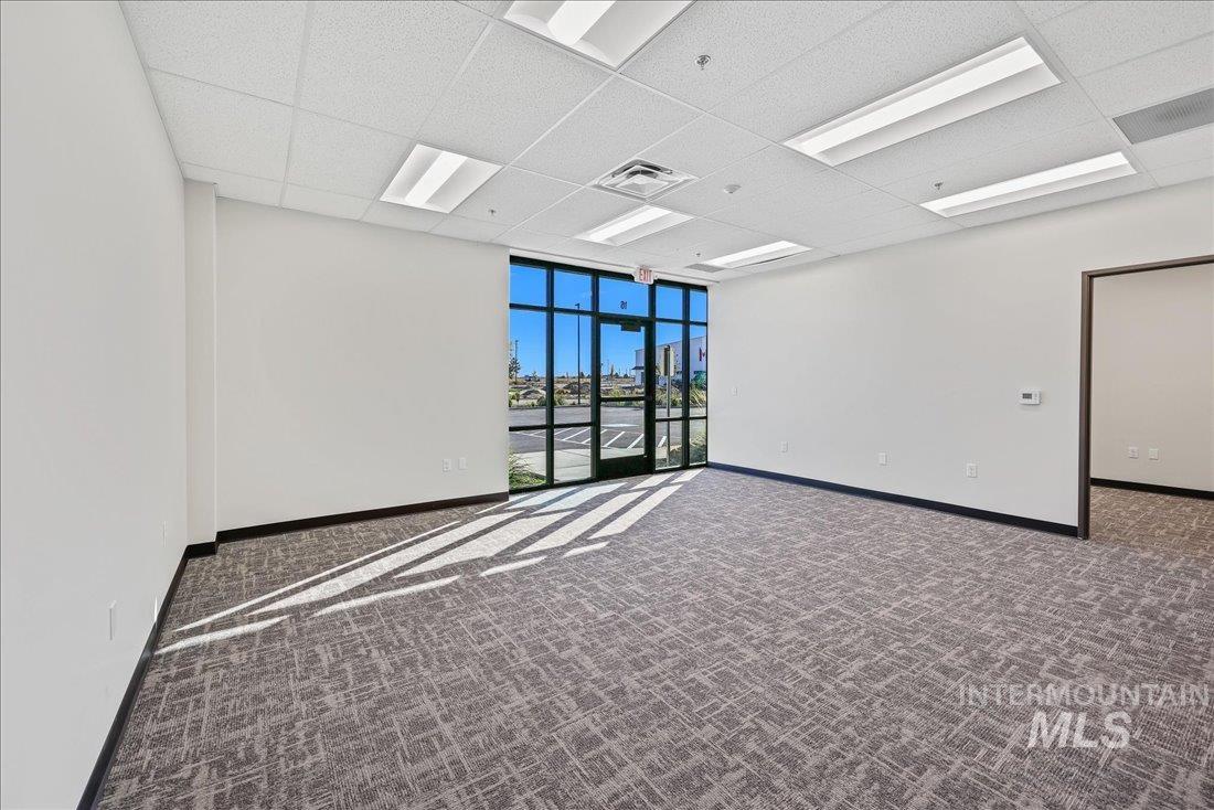 Unfurnished room with dark carpet, a drop ceiling, and floor to ceiling windows