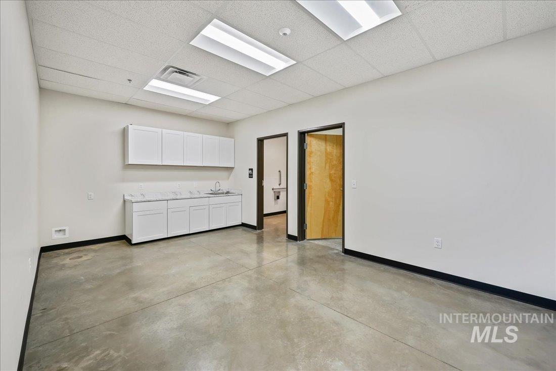 Empty room featuring a drop ceiling and finished concrete flooring