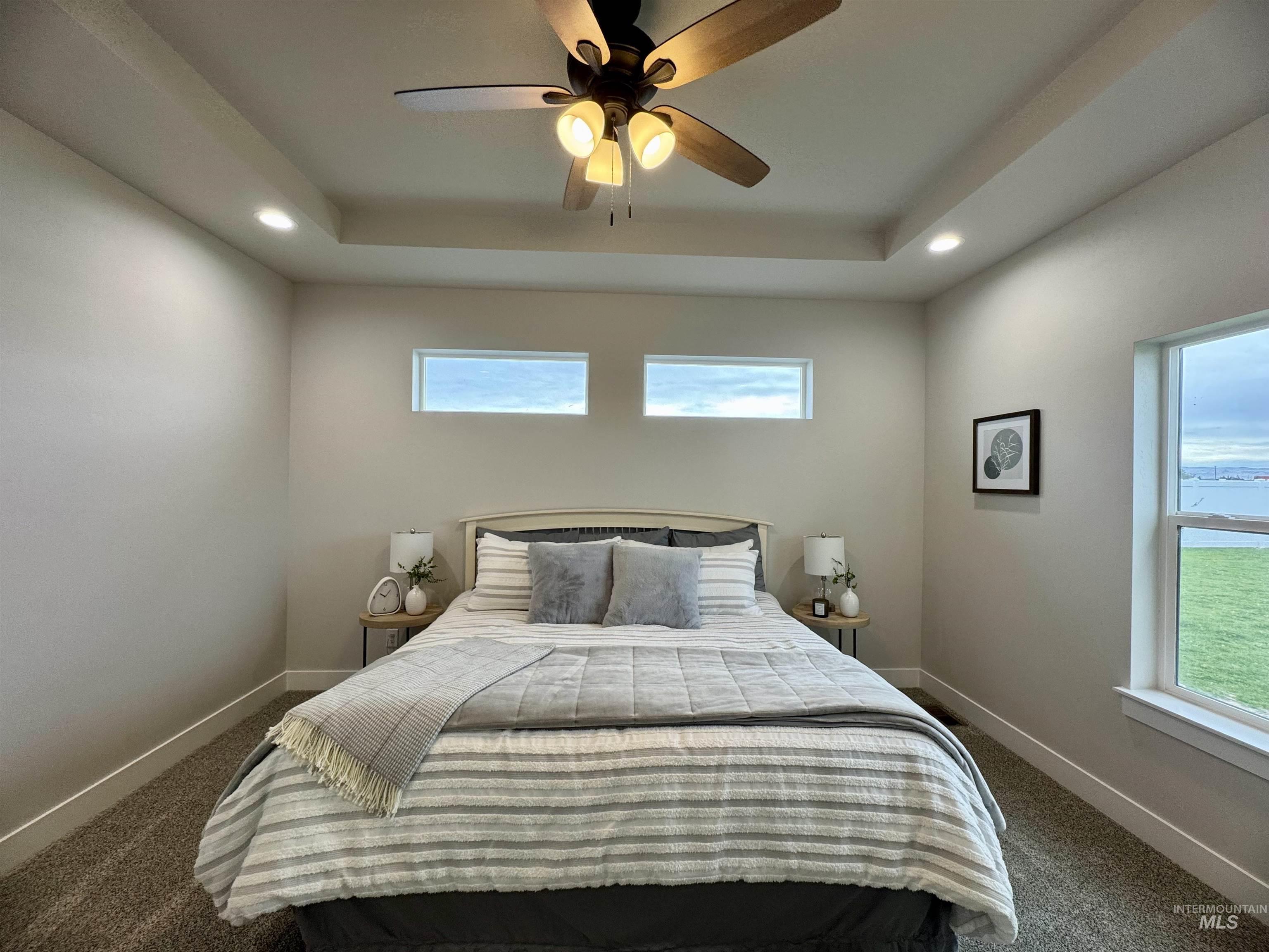 Bedroom featuring a raised ceiling, dark carpet, recessed lighting, and ceiling fan