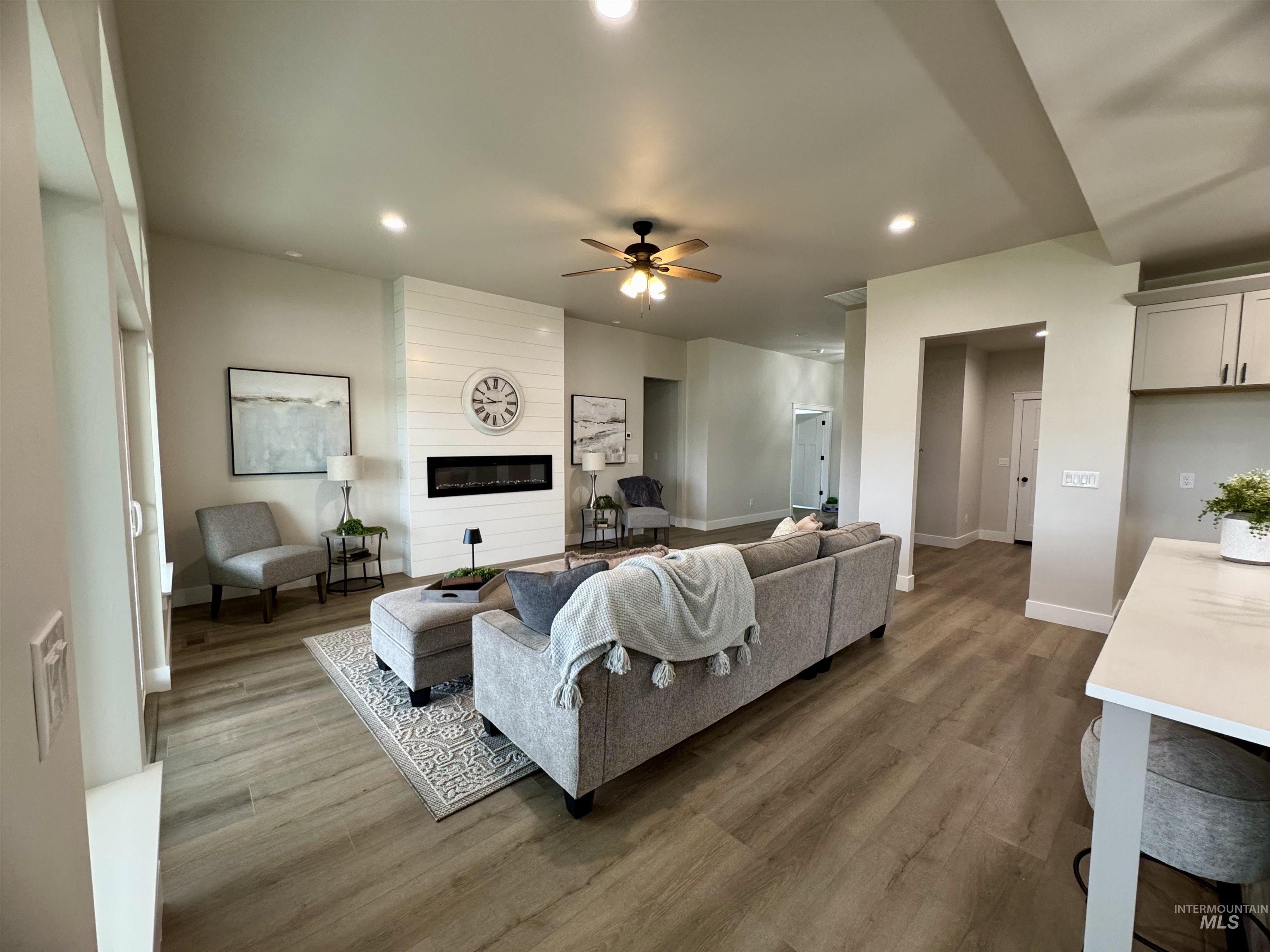 Living area featuring recessed lighting, wood finished floors, a large fireplace, and ceiling fan