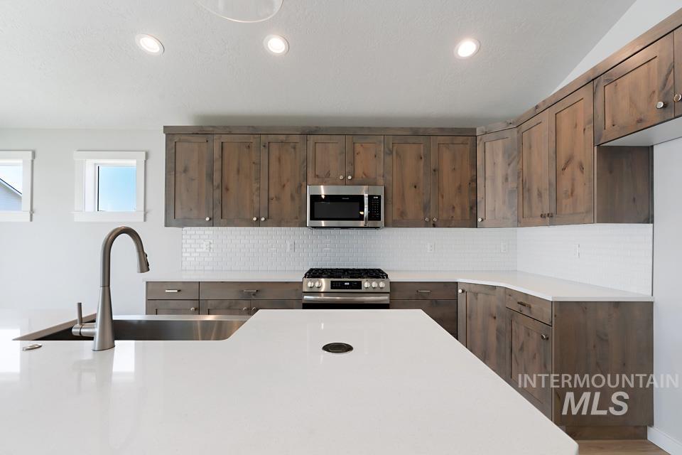 Kitchen with stainless steel appliances, tasteful backsplash, light countertops, and recessed lighting