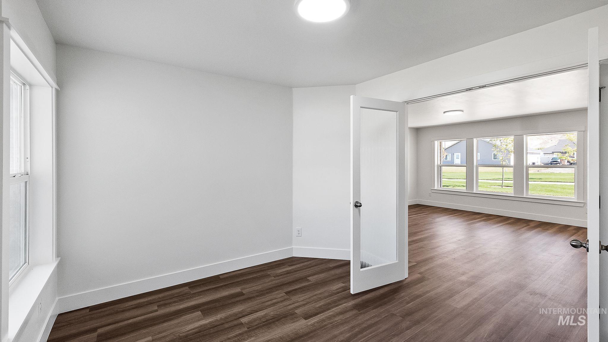 Empty room featuring dark wood finished floors and baseboards